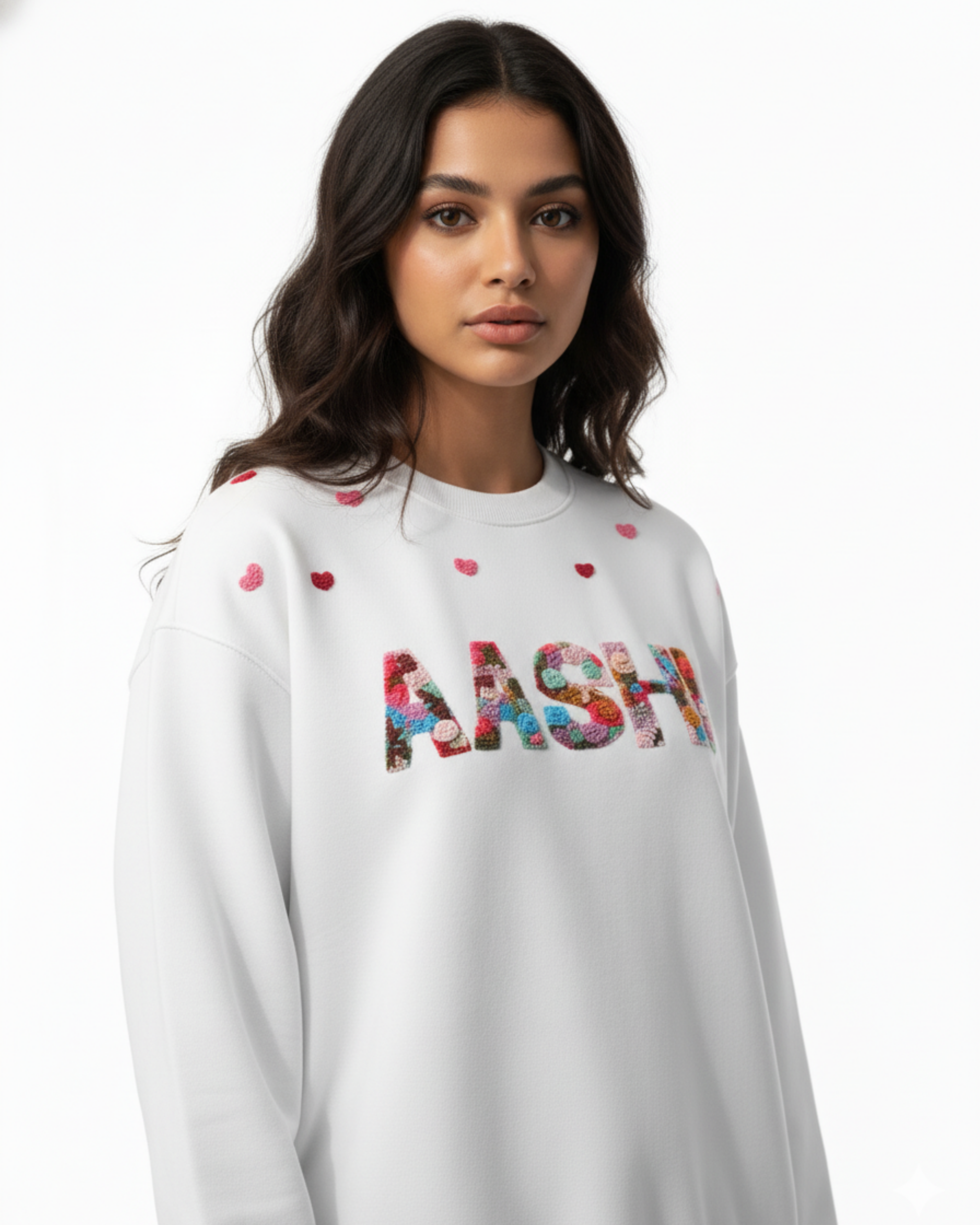 Woman wearing a white sweatshirt with colorful custom name hand embroidered  and heart patterns on a white background