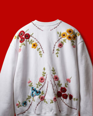 White sweatshirt with colorful floral embroidery on a red background