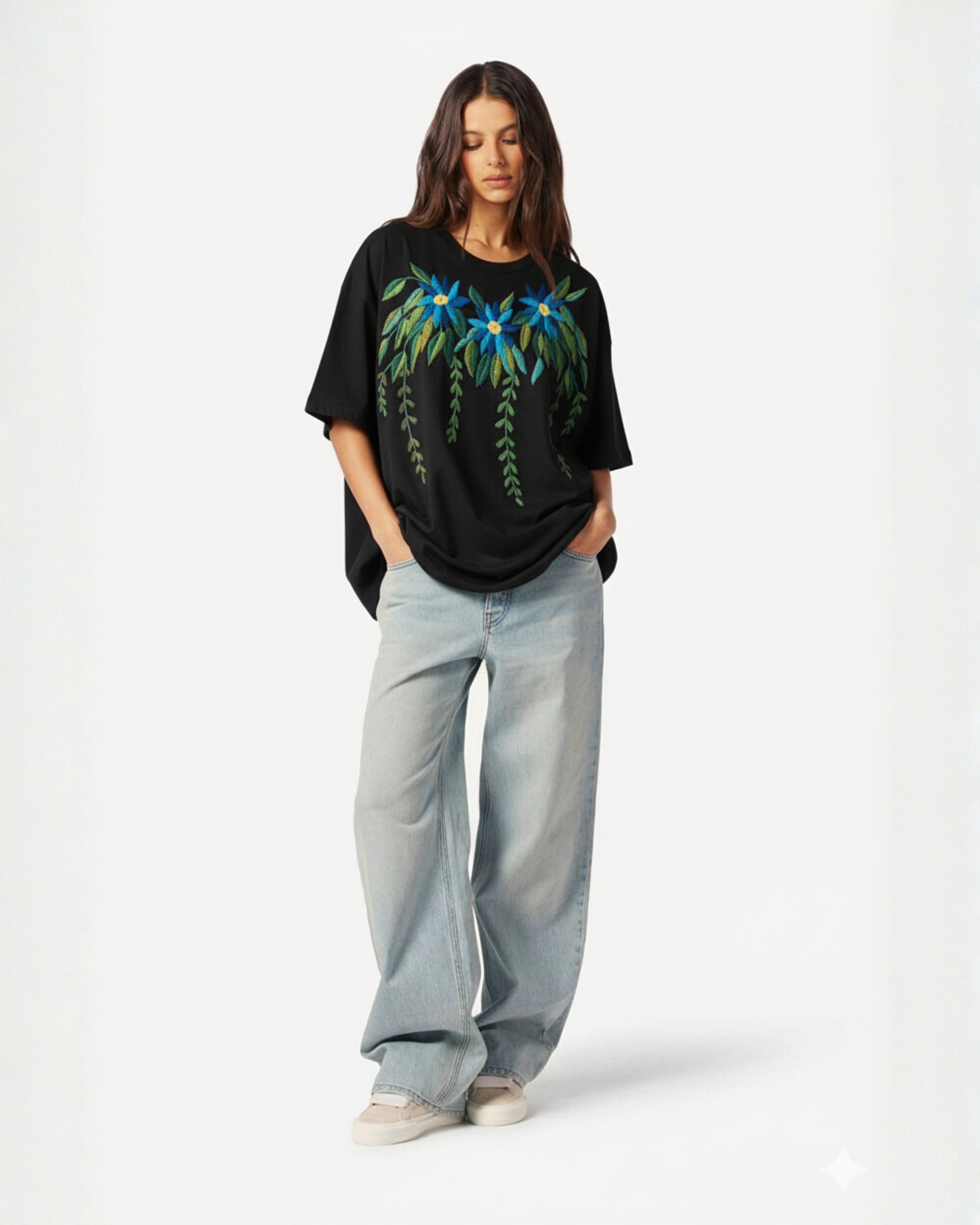 Woman wearing a black t-shirt with floral design hand embroidered and light blue jeans on a white background