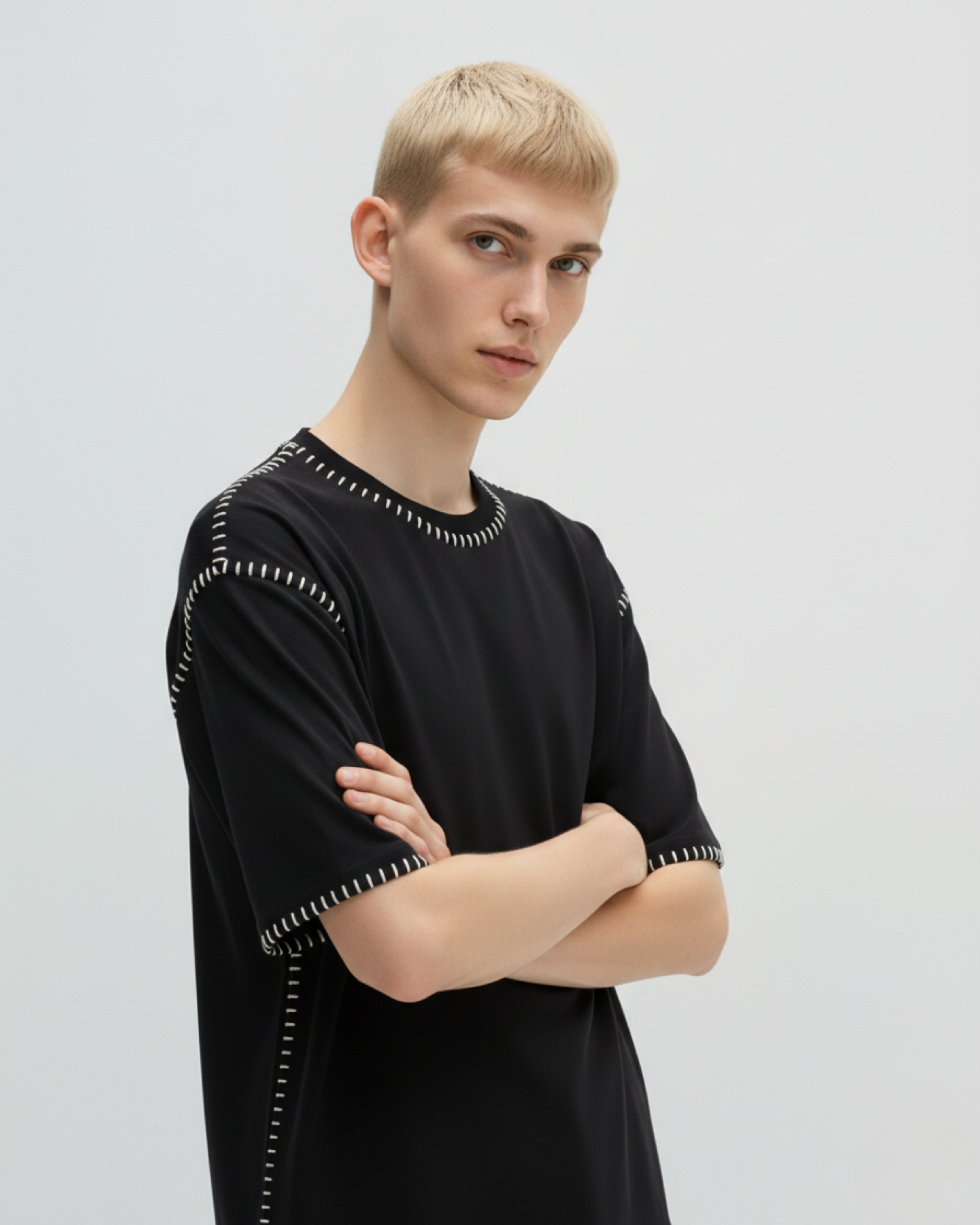 Person wearing a hand embroidered black outfit with white patterns on a light gray background