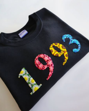 Flat lay of black t-shirt with custom hand-embroidered year and number