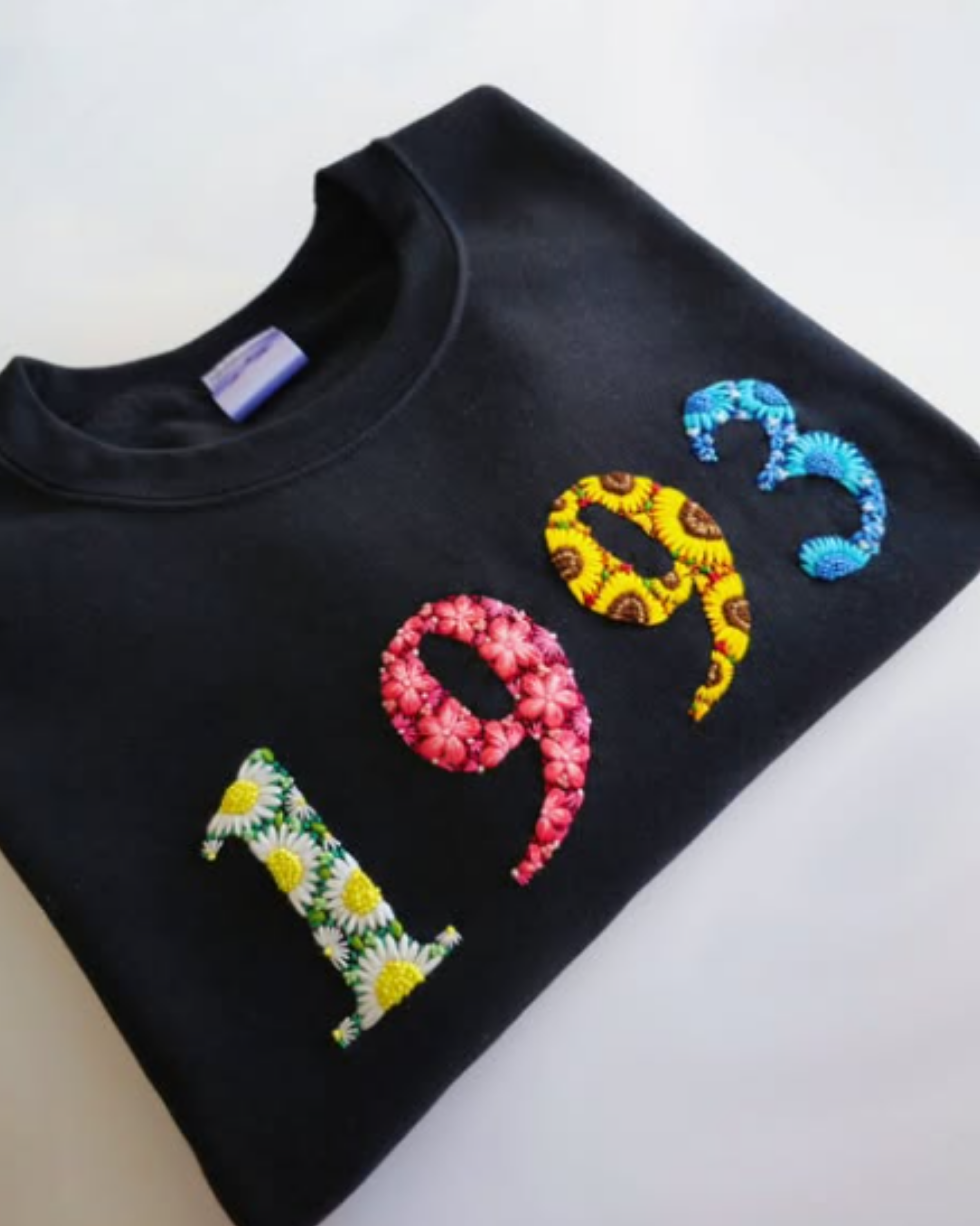 Flat lay of black t-shirt with custom hand-embroidered year and number