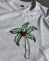 White t-shirt with a palm tree design  bead embroidered on a dark background