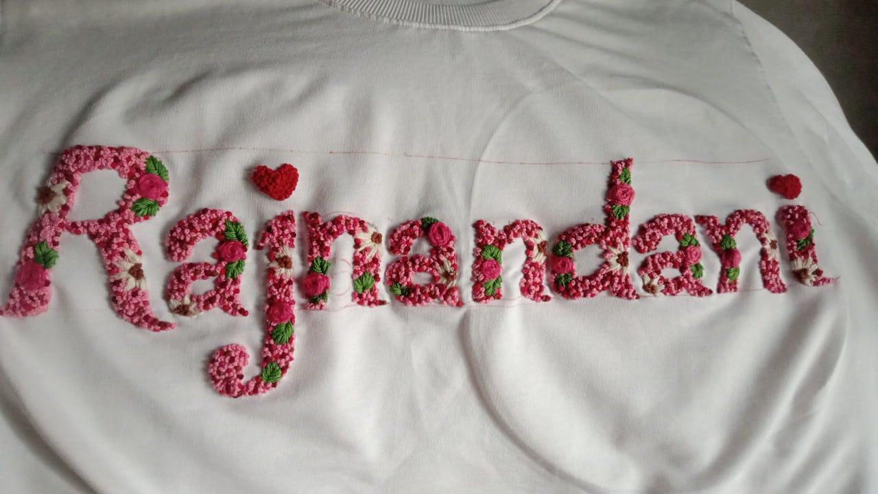 White shirt with 'Rajnandani' embroidered in pink and red letters.