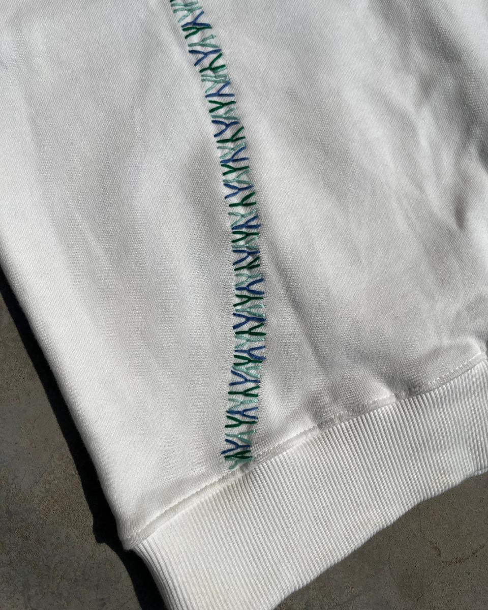 Close-up of a white garment with green stitching on a gray background