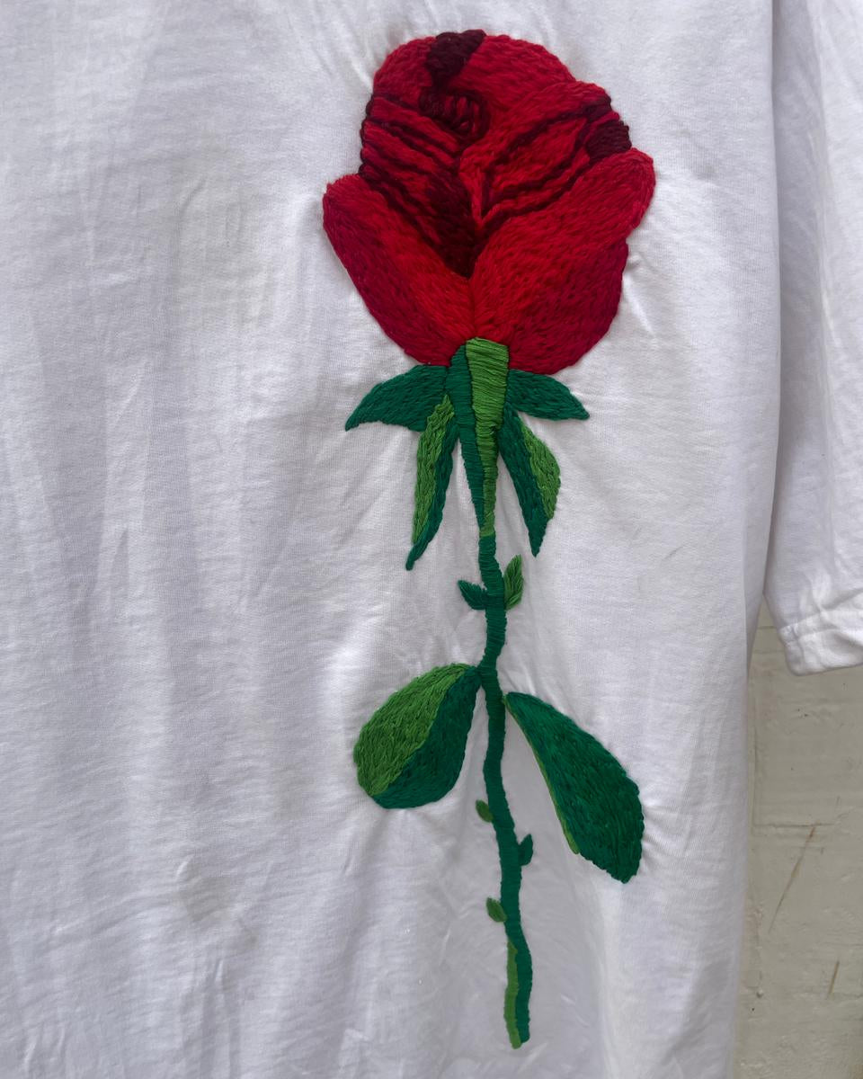 Embroidered red rose on a white fabric background