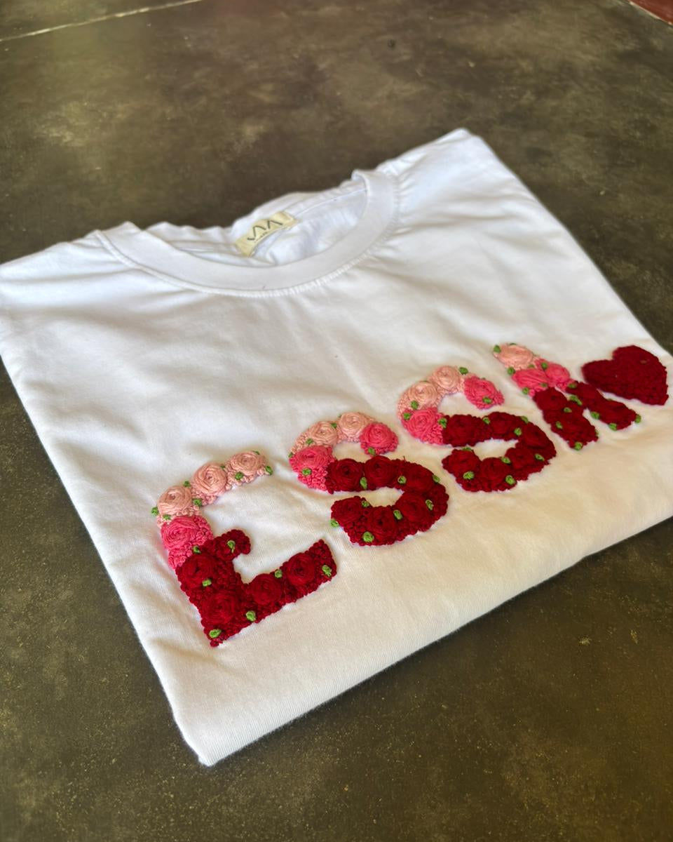 Floral name embroidery double shade tee — white tee with floral hand-embroidered text design on dark surface, two-tone thread work