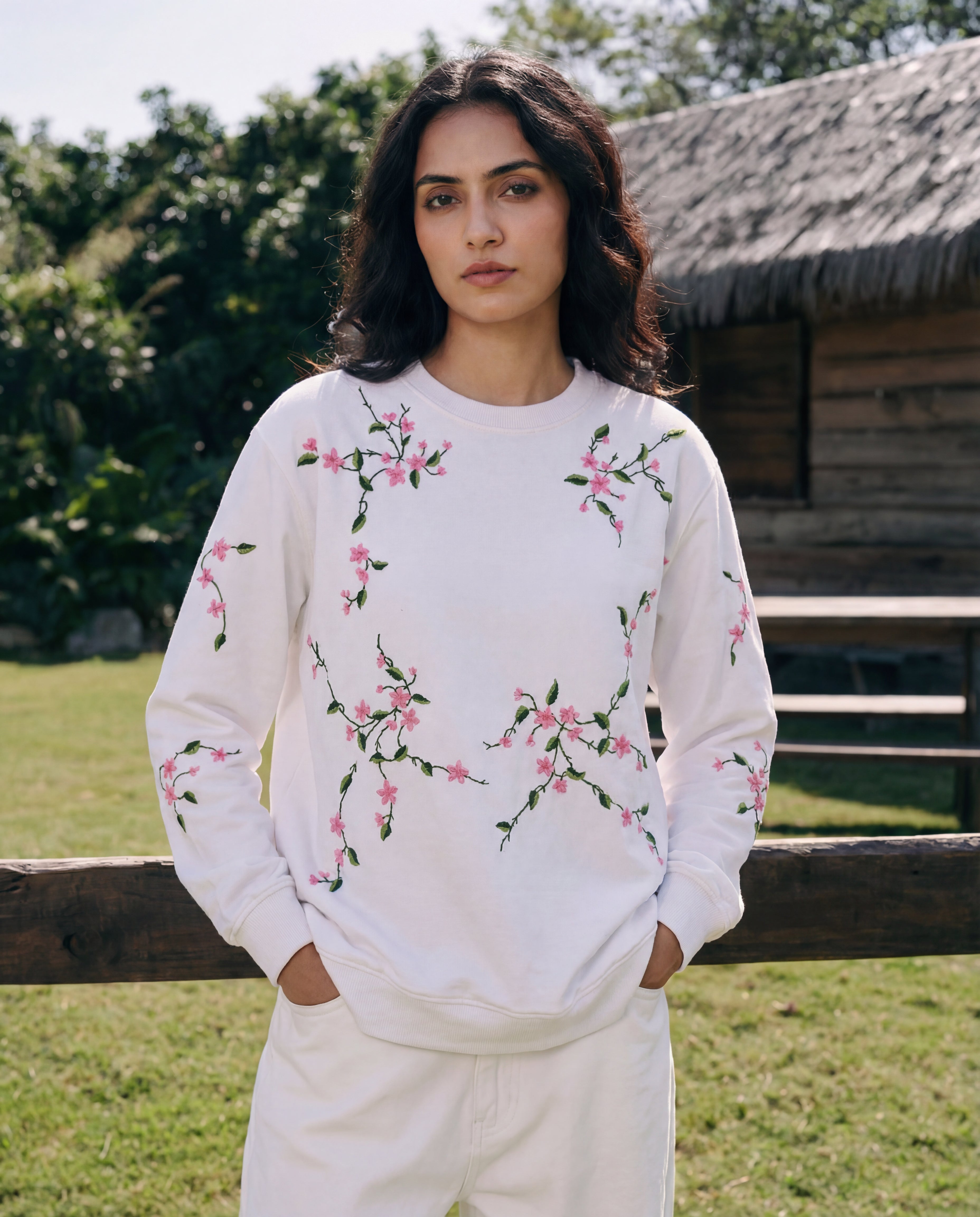 Woman wearing a white sweatshirt with floral embroidery in a natural setting