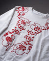 White sweatshirt with red floral embroidery on a dark background