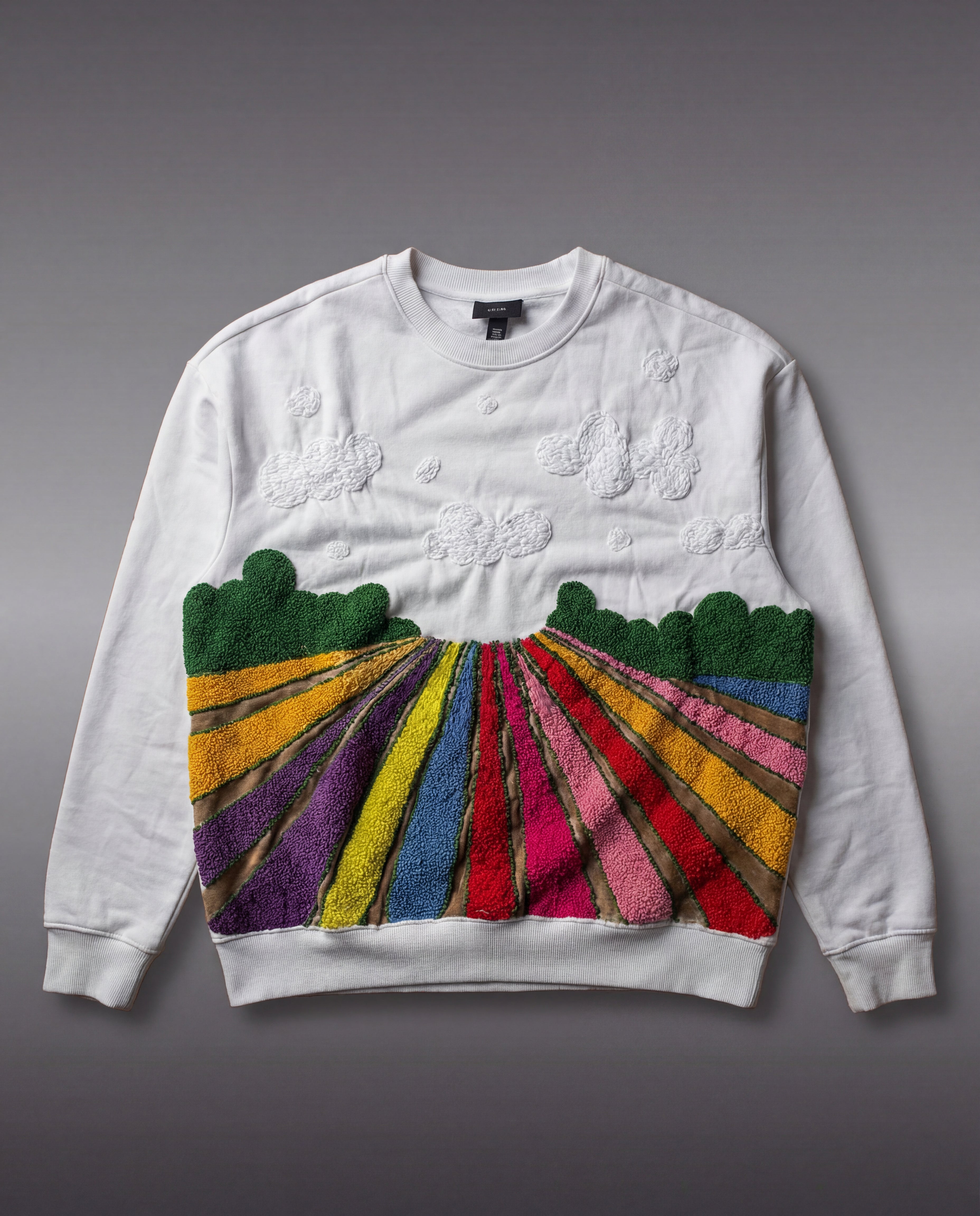 White sweatshirt with colorful field embroidered design on a gray background
