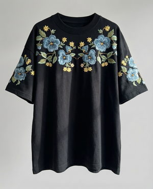 Black t-shirt with floral embroidery on a gray background