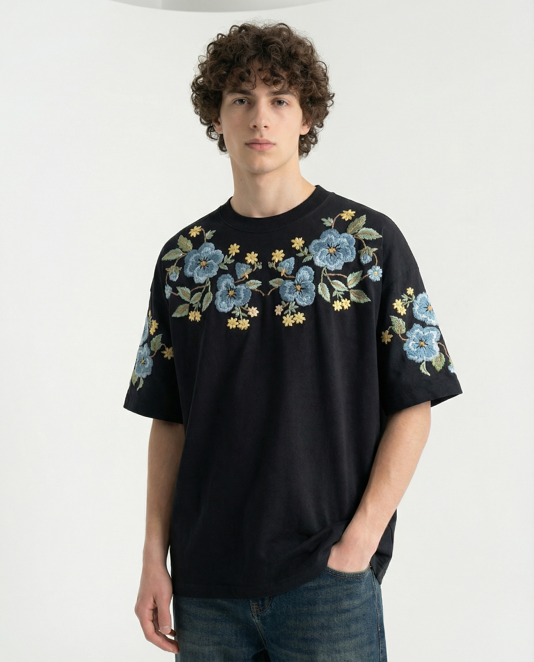 Person wearing a black t-shirt with floral embroidery on a white background