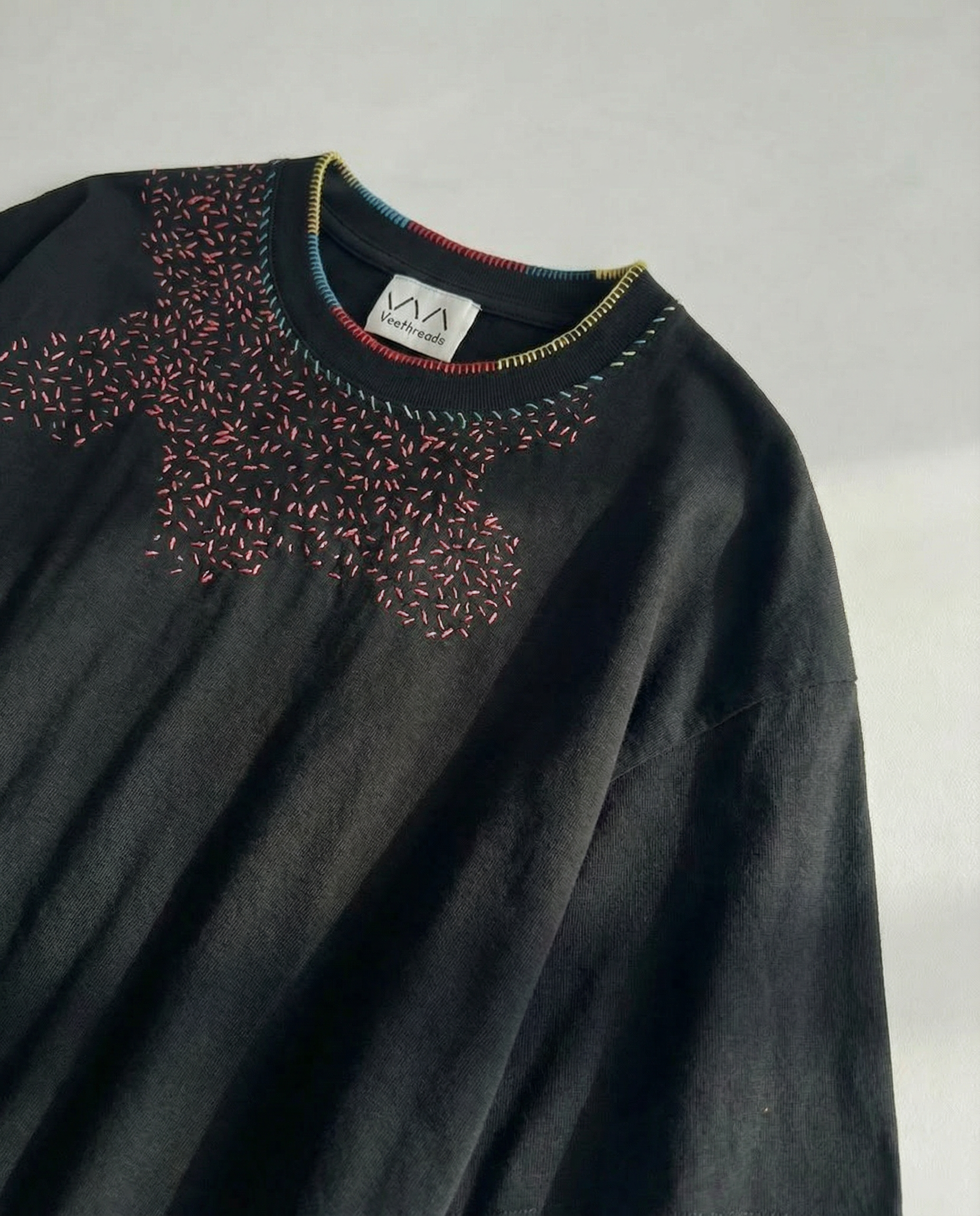 Black sweater with colorful embroidery on a white background