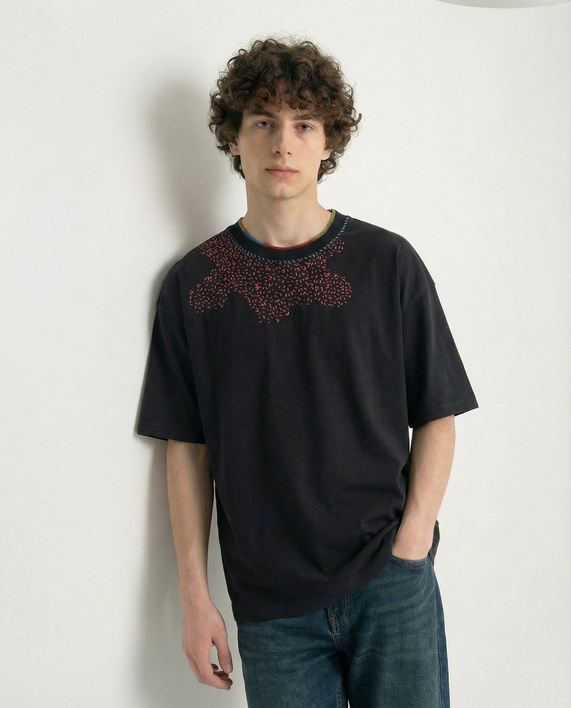 Person wearing a black t-shirt with a pattern on a plain background