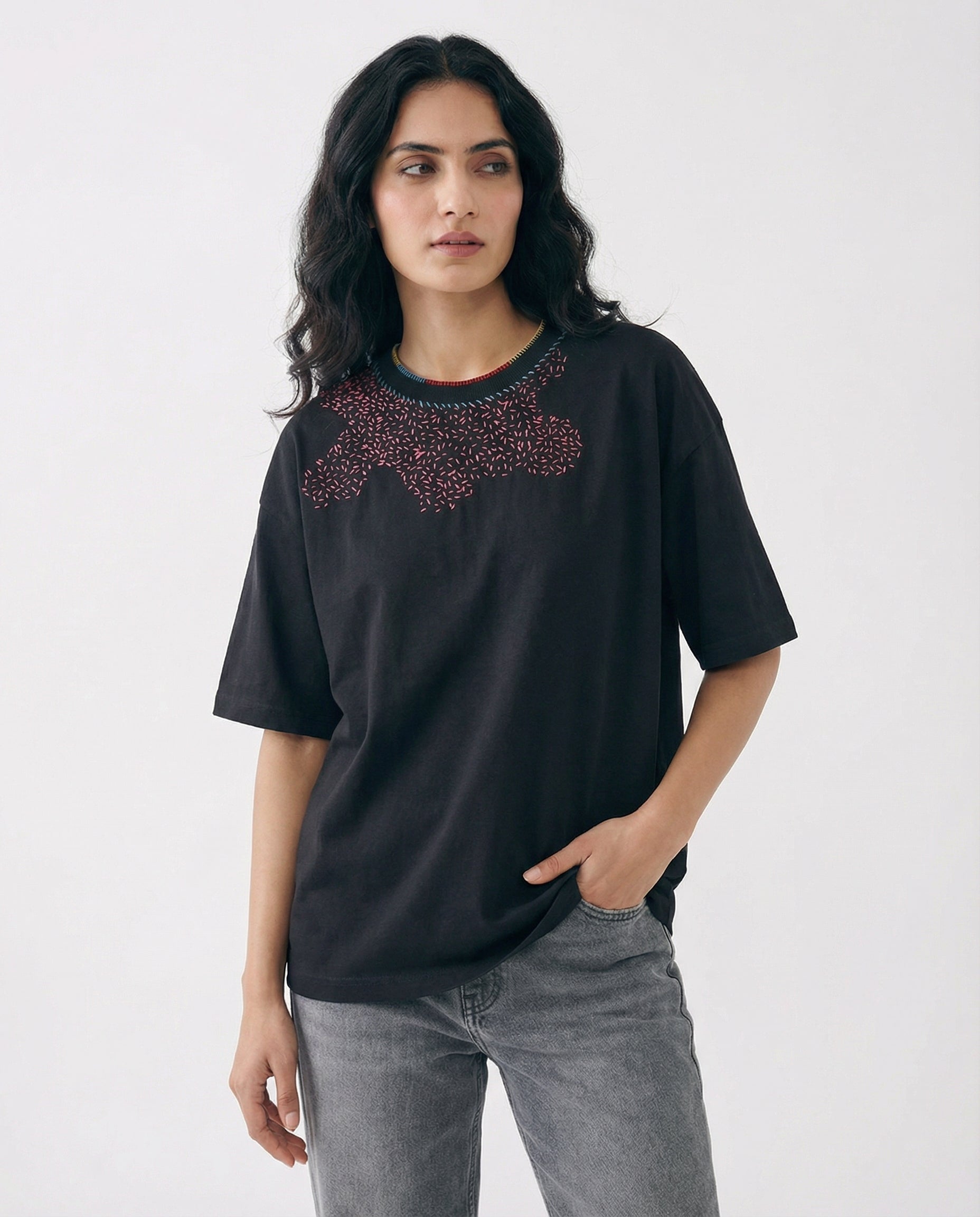 Woman wearing a black t-shirt with decorative neckline on a white background
