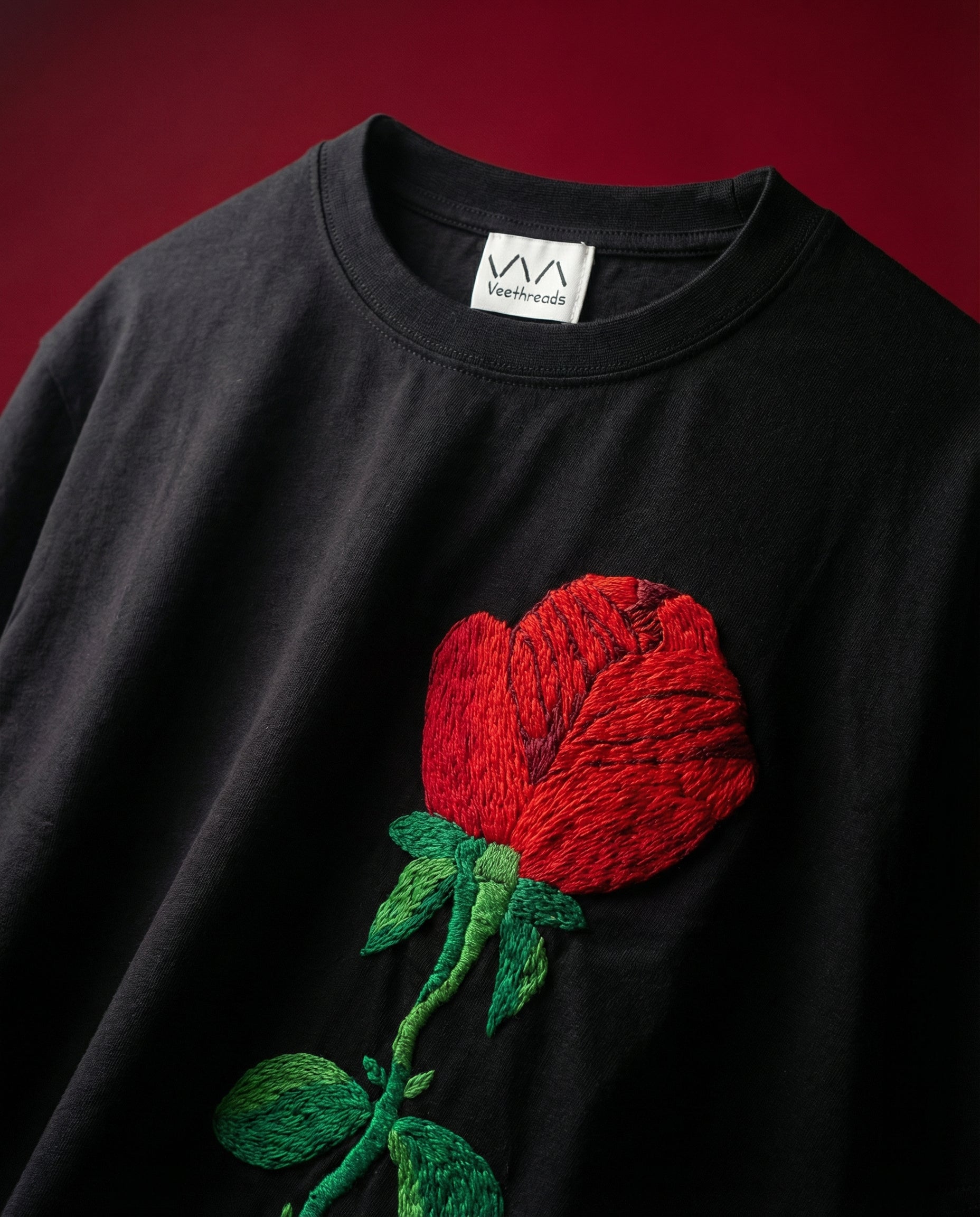 Black t-shirt with a red embroidered rose on a dark background