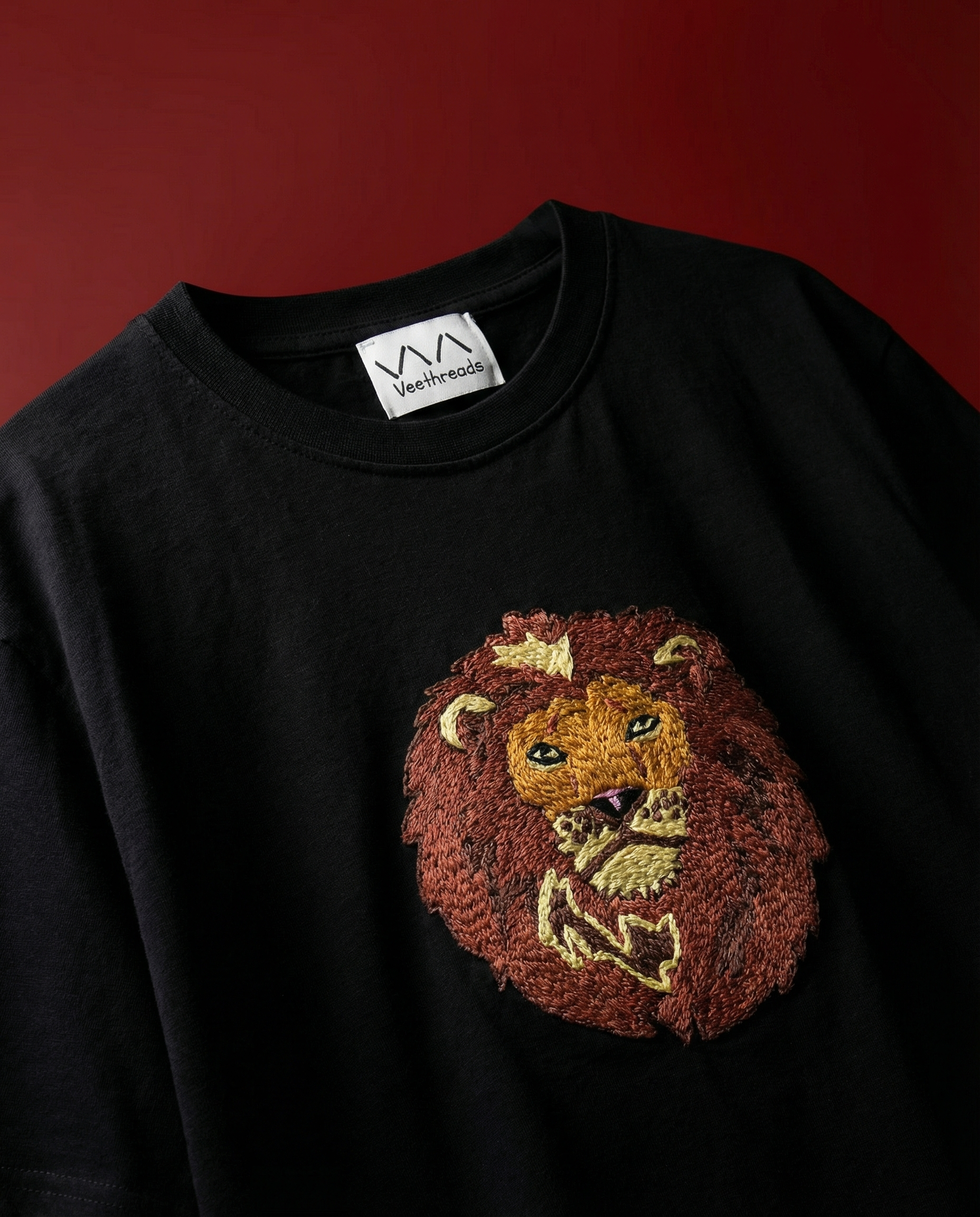 Black shirt with a lion embroidered  on a red background
