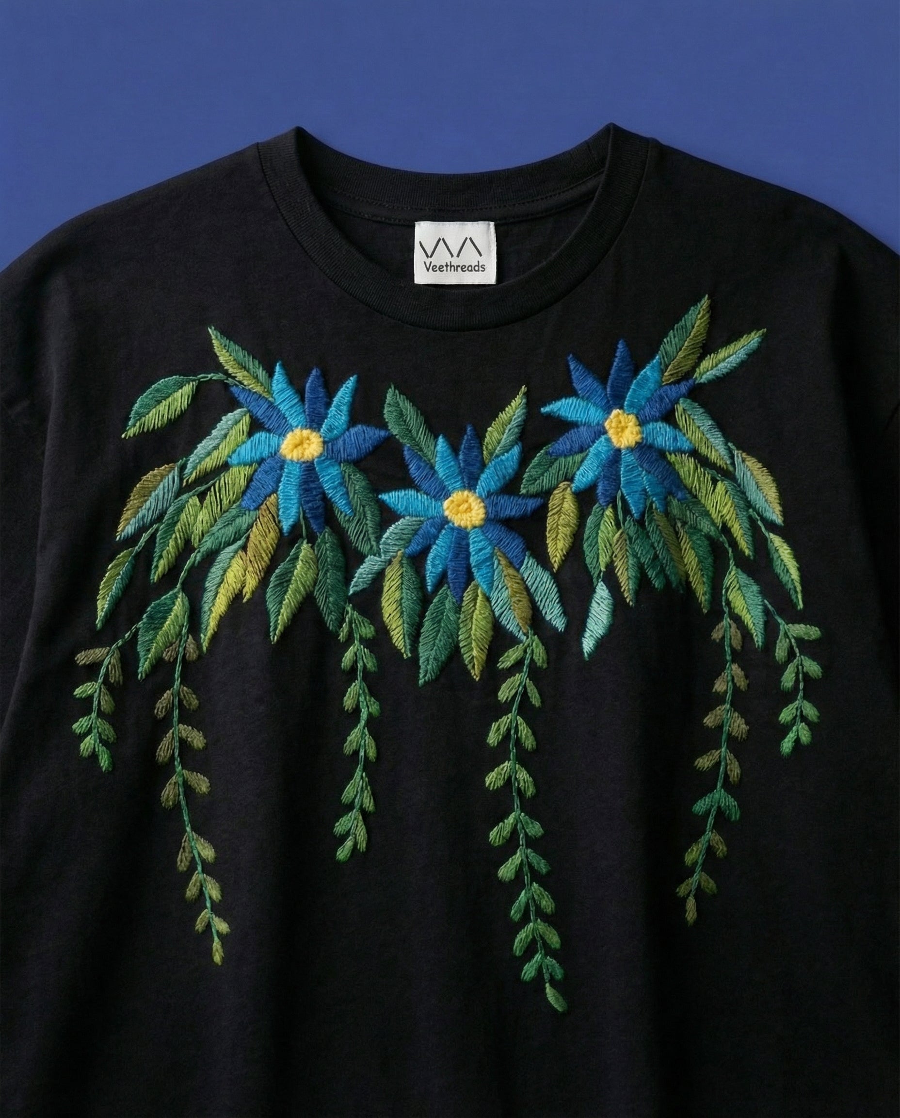 Black shirt with blue and green floral embroidery on a blue background