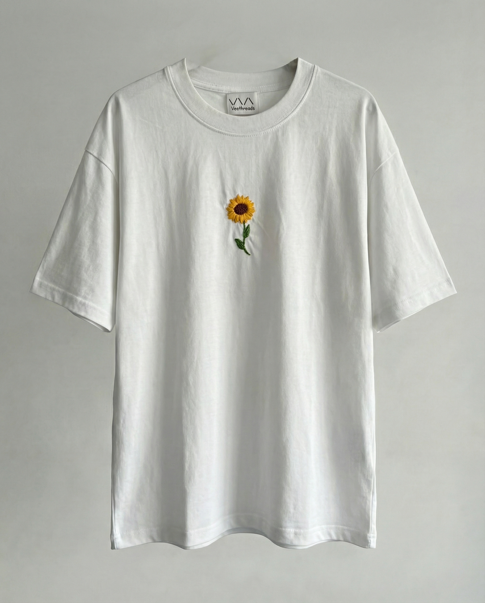White t-shirt with a sunflower design on a gray background