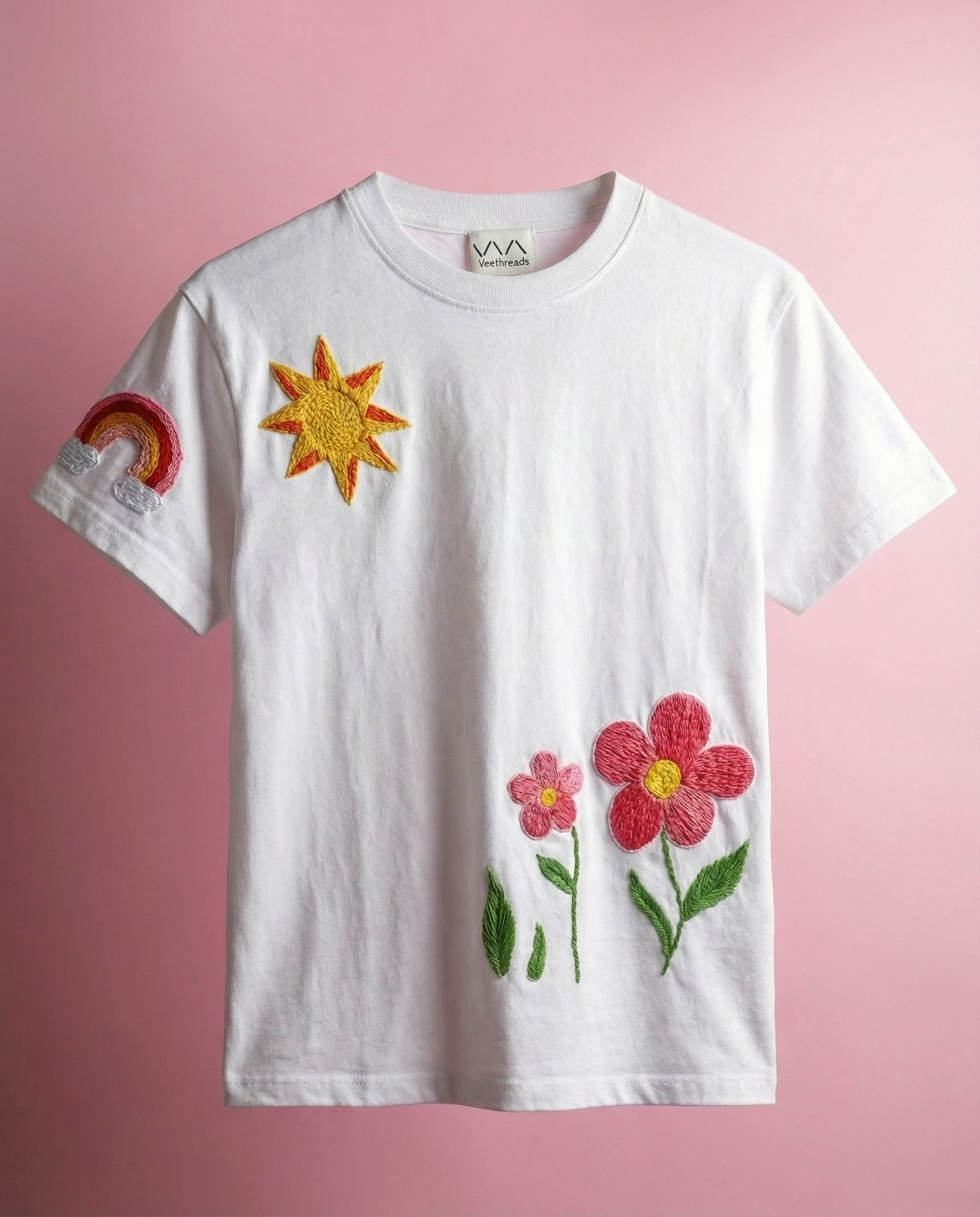 White t-shirt with embroidered sun and flowers on a pink background