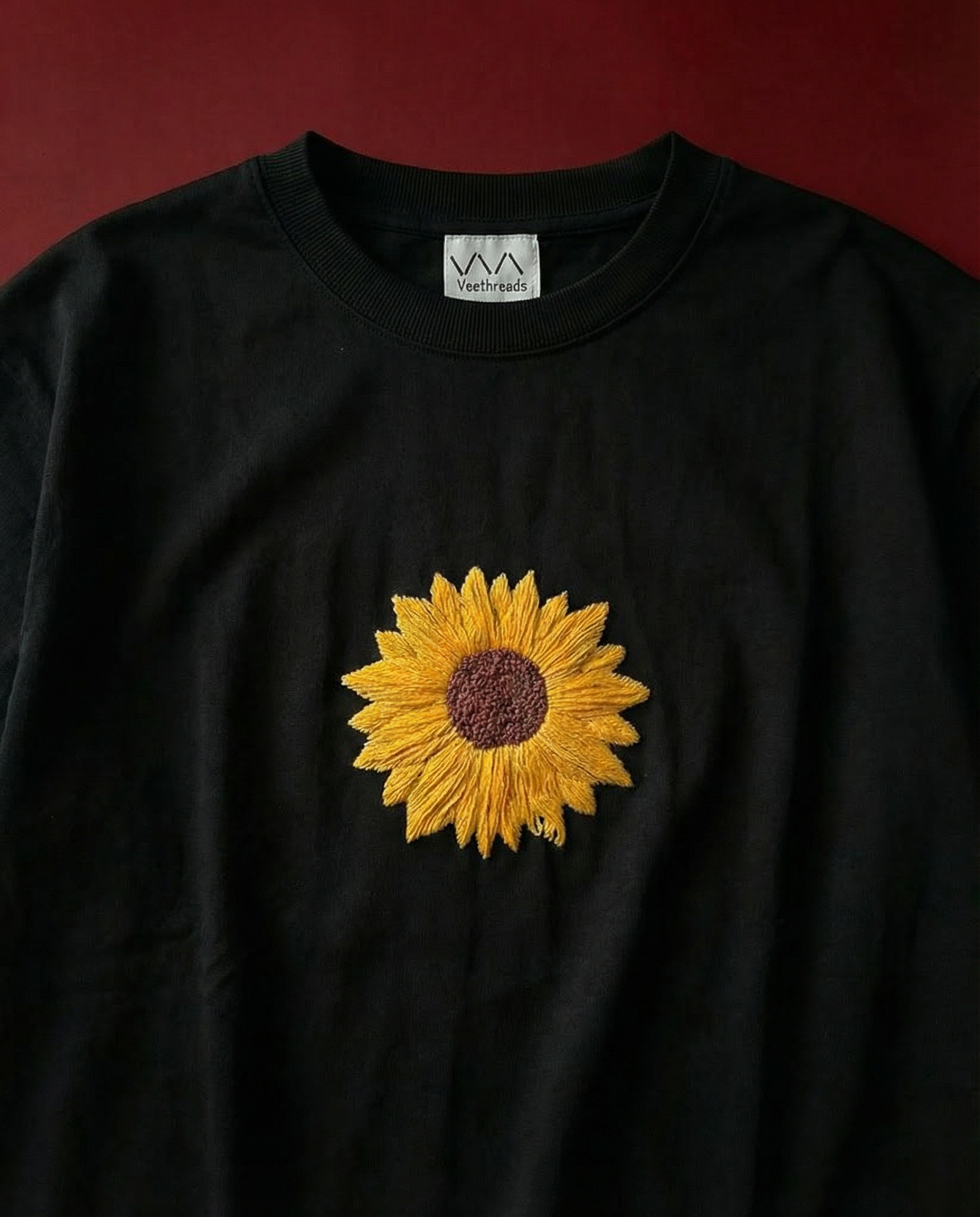 Black sweatshirt with a embroidered sunflower design on a red background