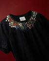 Black t-shirt with floral embroidery on a red background