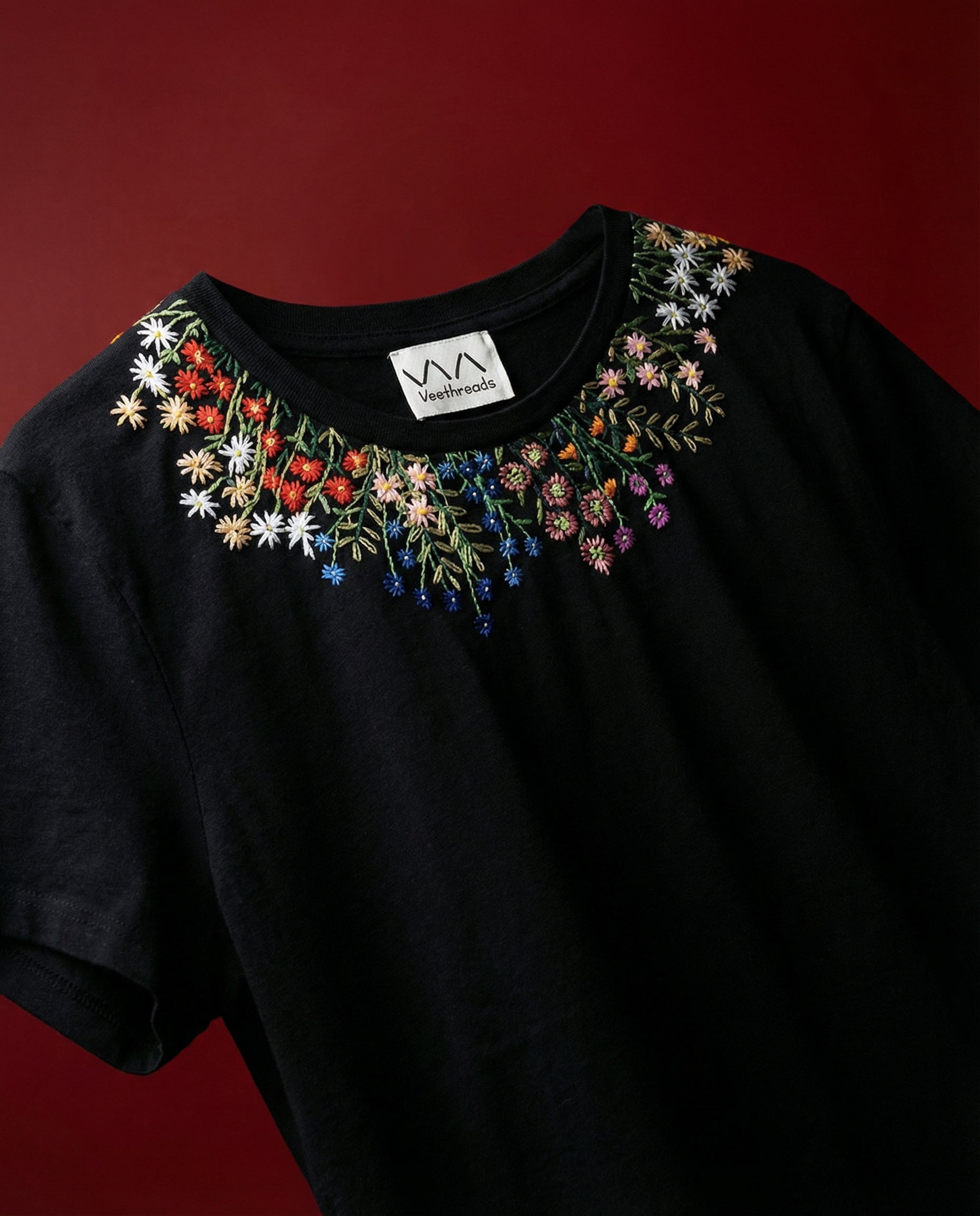 Black t-shirt with floral embroidery on a red background