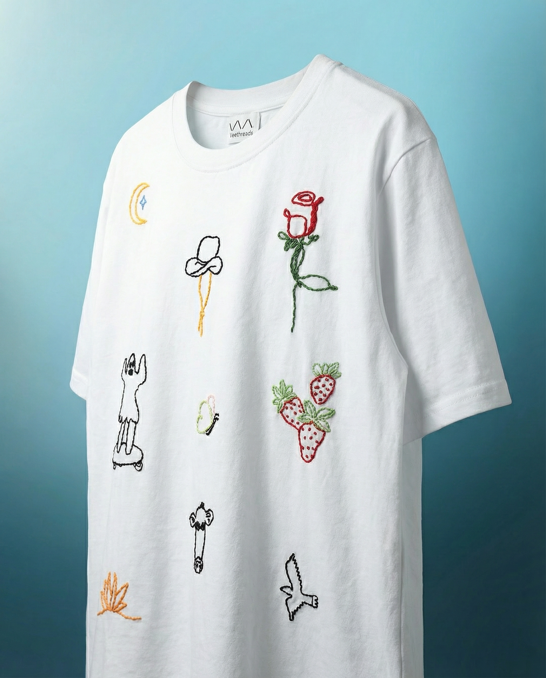 White t-shirt with colorful rose embroidered designs on a blue background