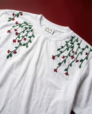 White shirt with red and green floral embroidery on a red background