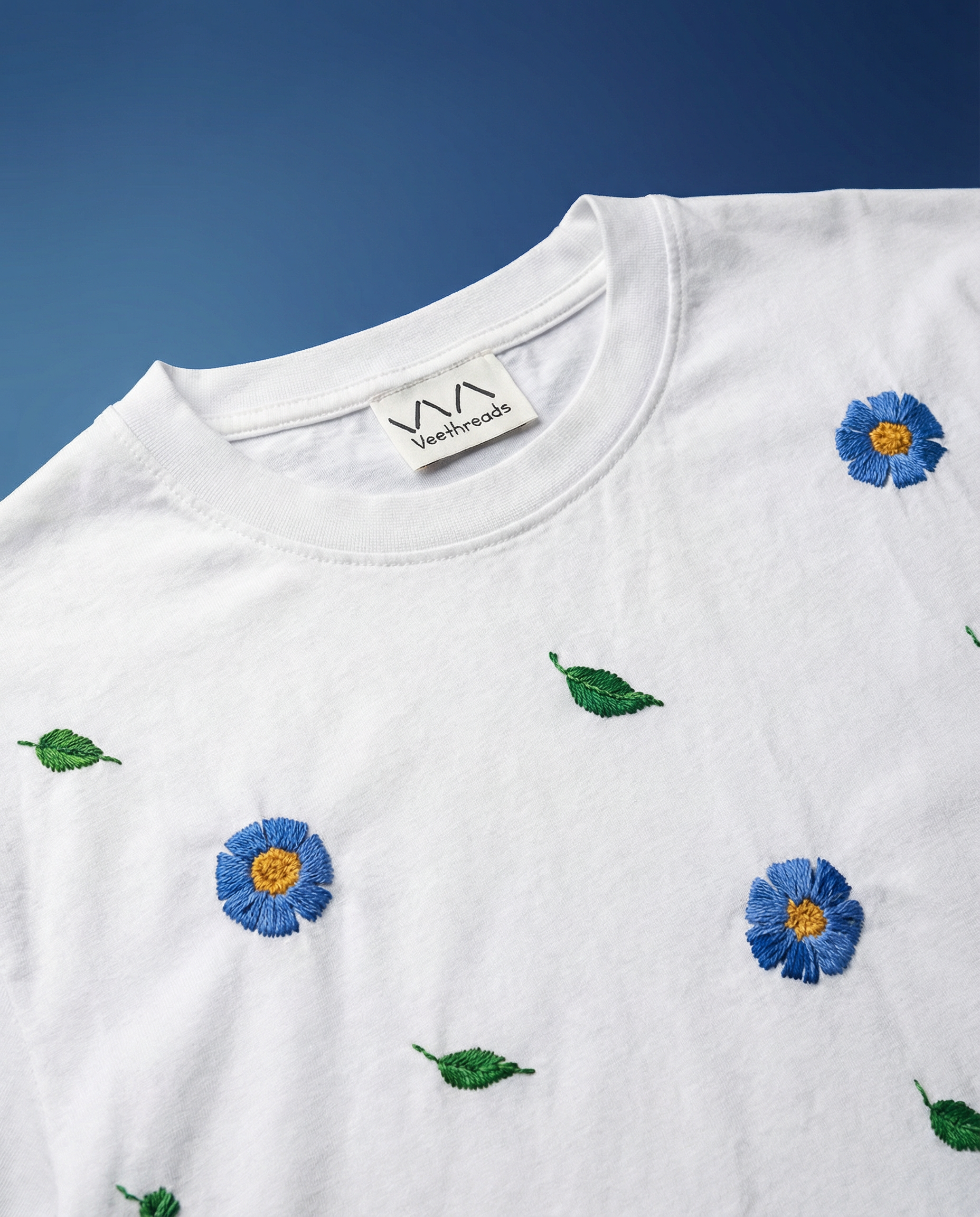 Azure Bloom — blue florals hand-embroidered on a white 220 GSM cotton oversized tee, soft pastel thread, oversized unisex fit.