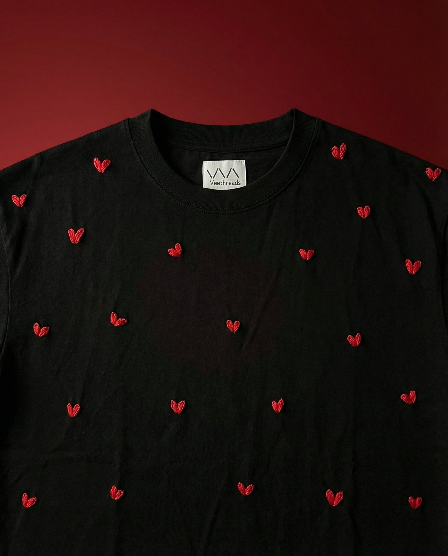 Black t-shirt with red heart patterns on a red background