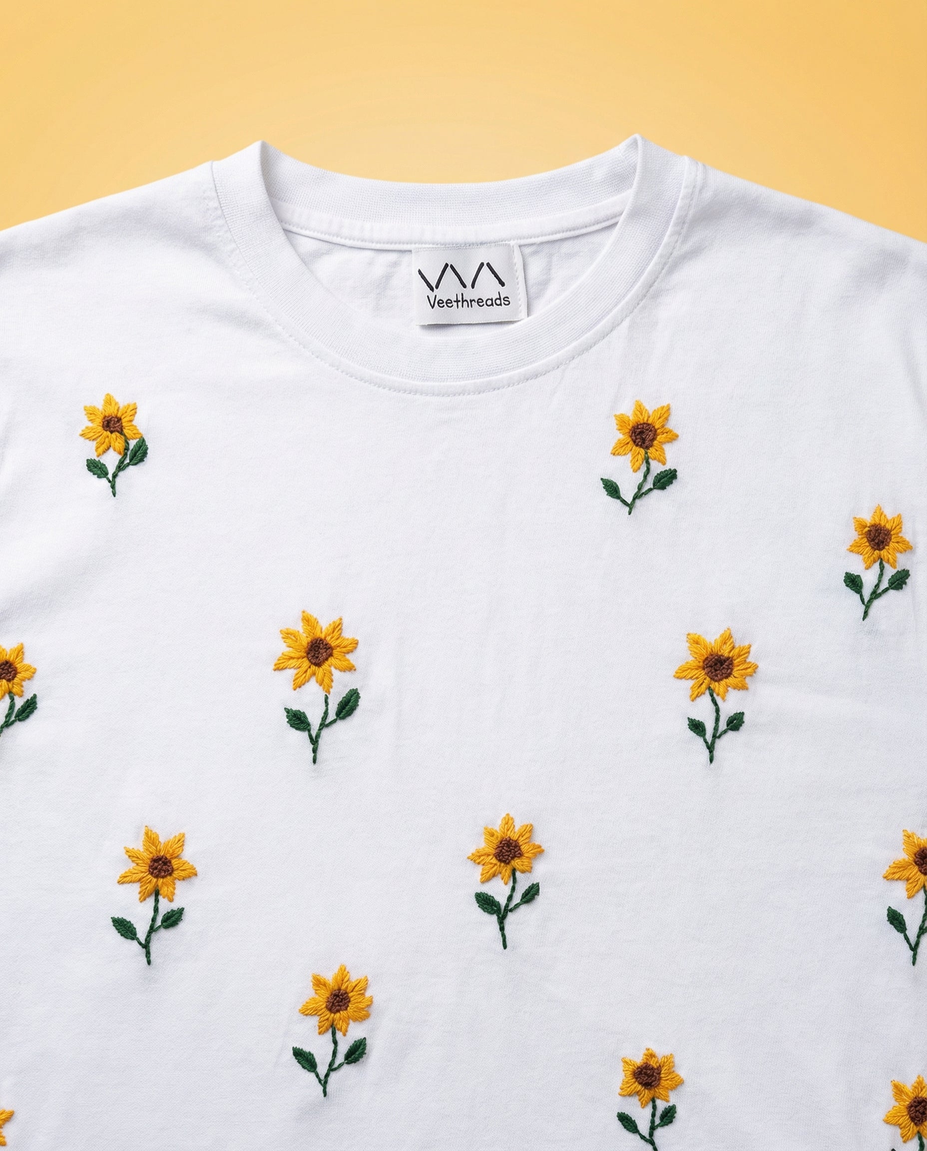 White t-shirt with embroidered yellow flowers on a yellow background