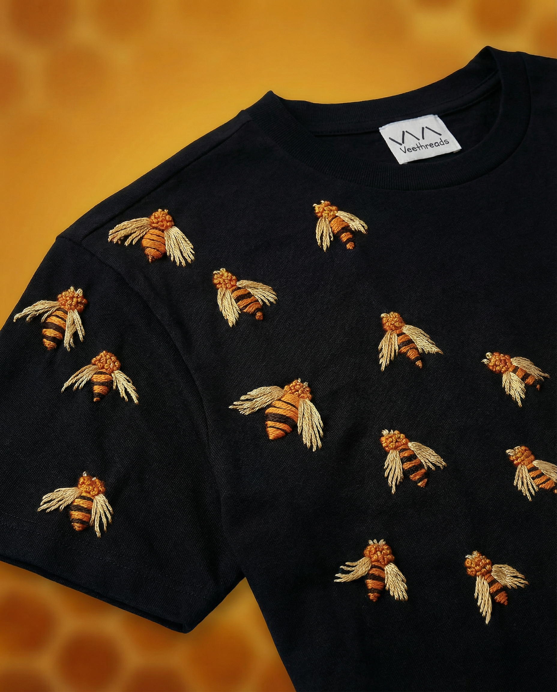 Black t-shirt with embroidered bees on a honeycomb background