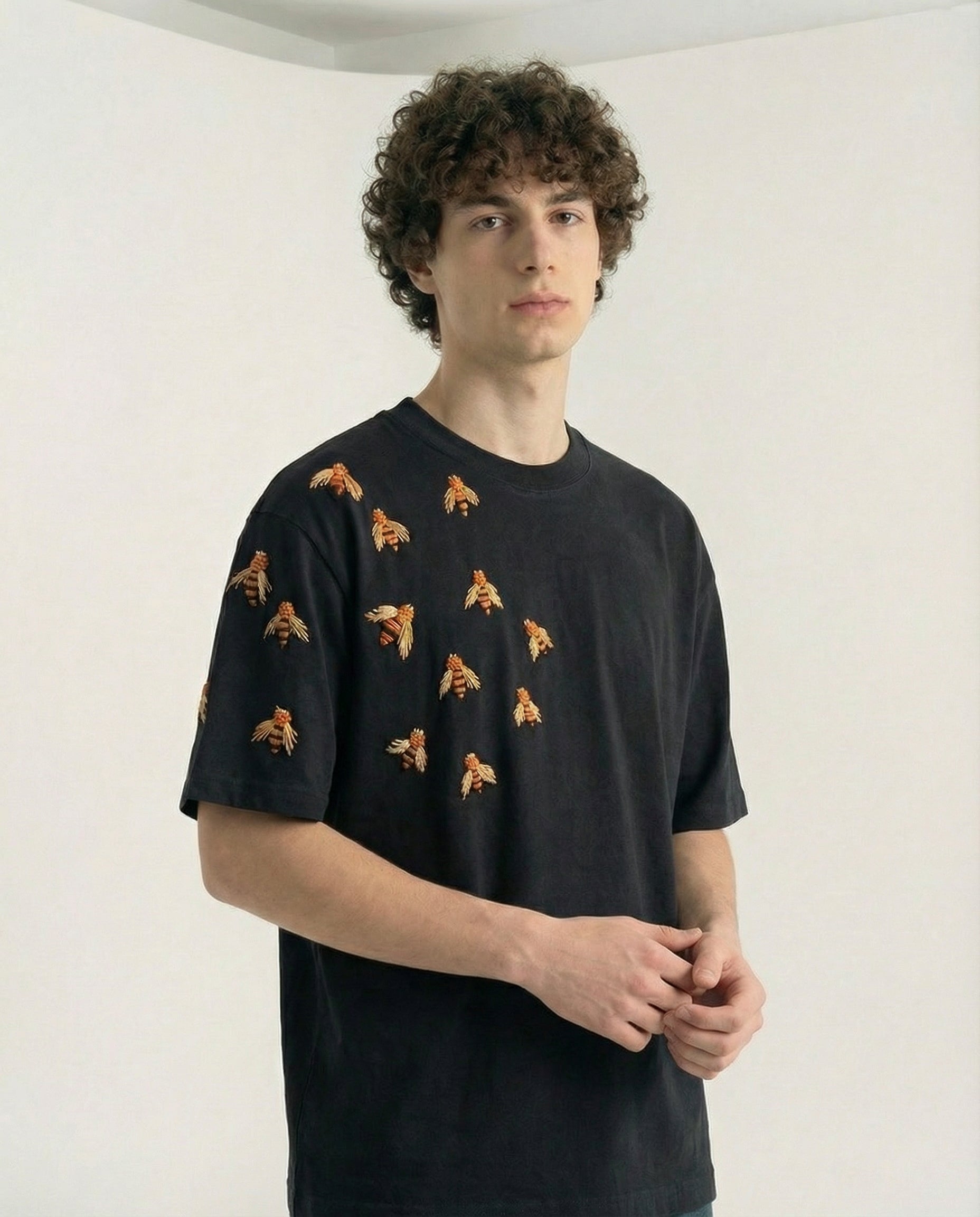 Person wearing a black t-shirt with small graphic patterns on a plain background