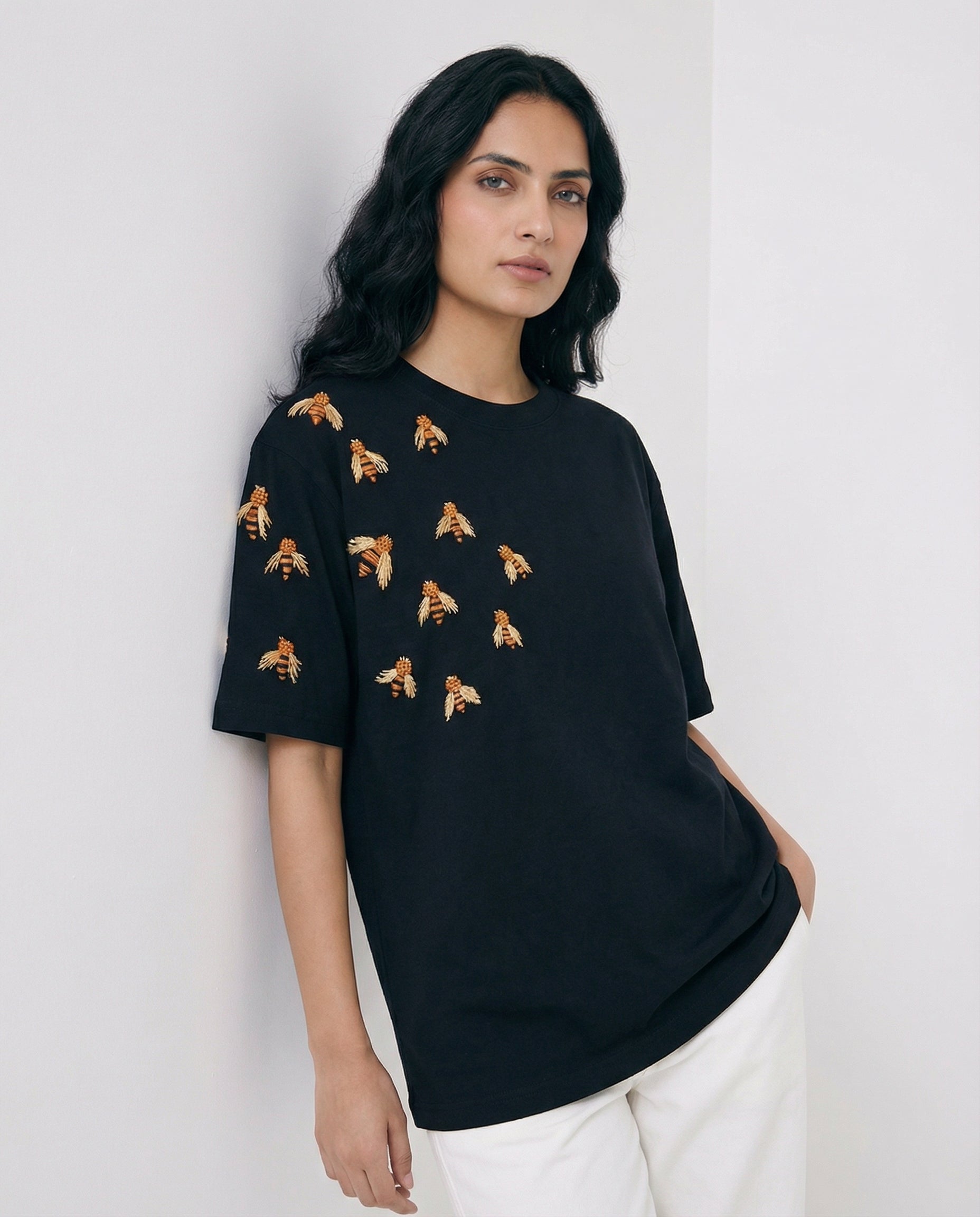 Woman wearing a black t-shirt with small patterns on a plain background