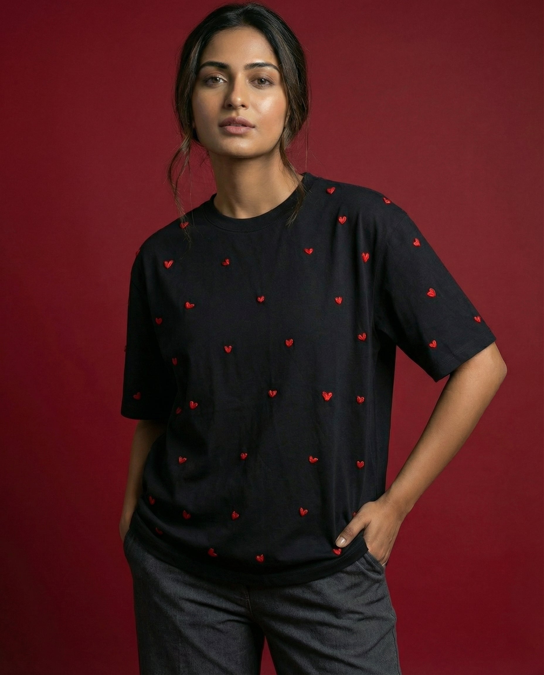 Woman wearing a black t-shirt with red heart patterns against a red background
