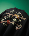 Black tshirt with embroidered sloth and branch design on a green background