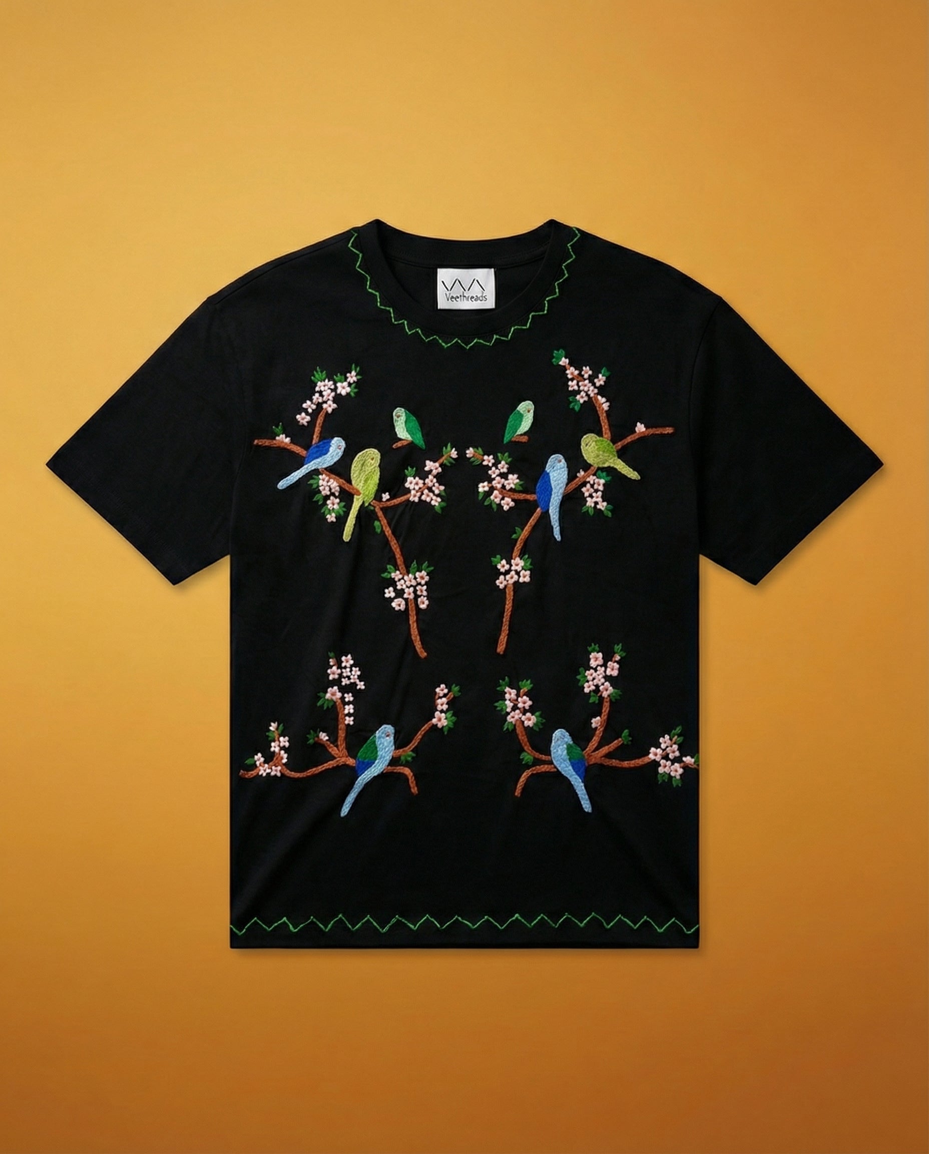 Black t-shirt with colorful bird and branch design on a yellow background