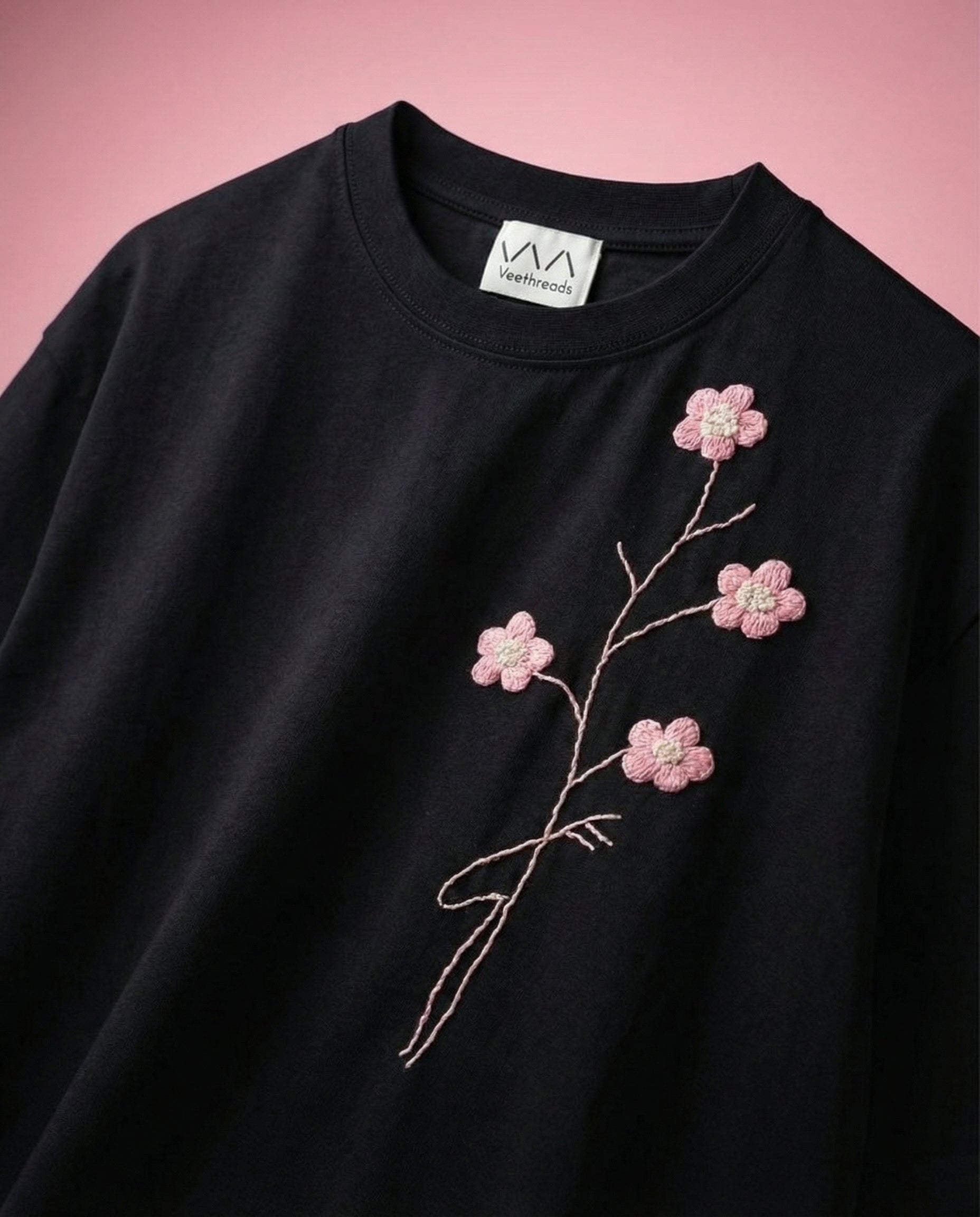 Black sweatshirt with pink floral embroidery on a pink background