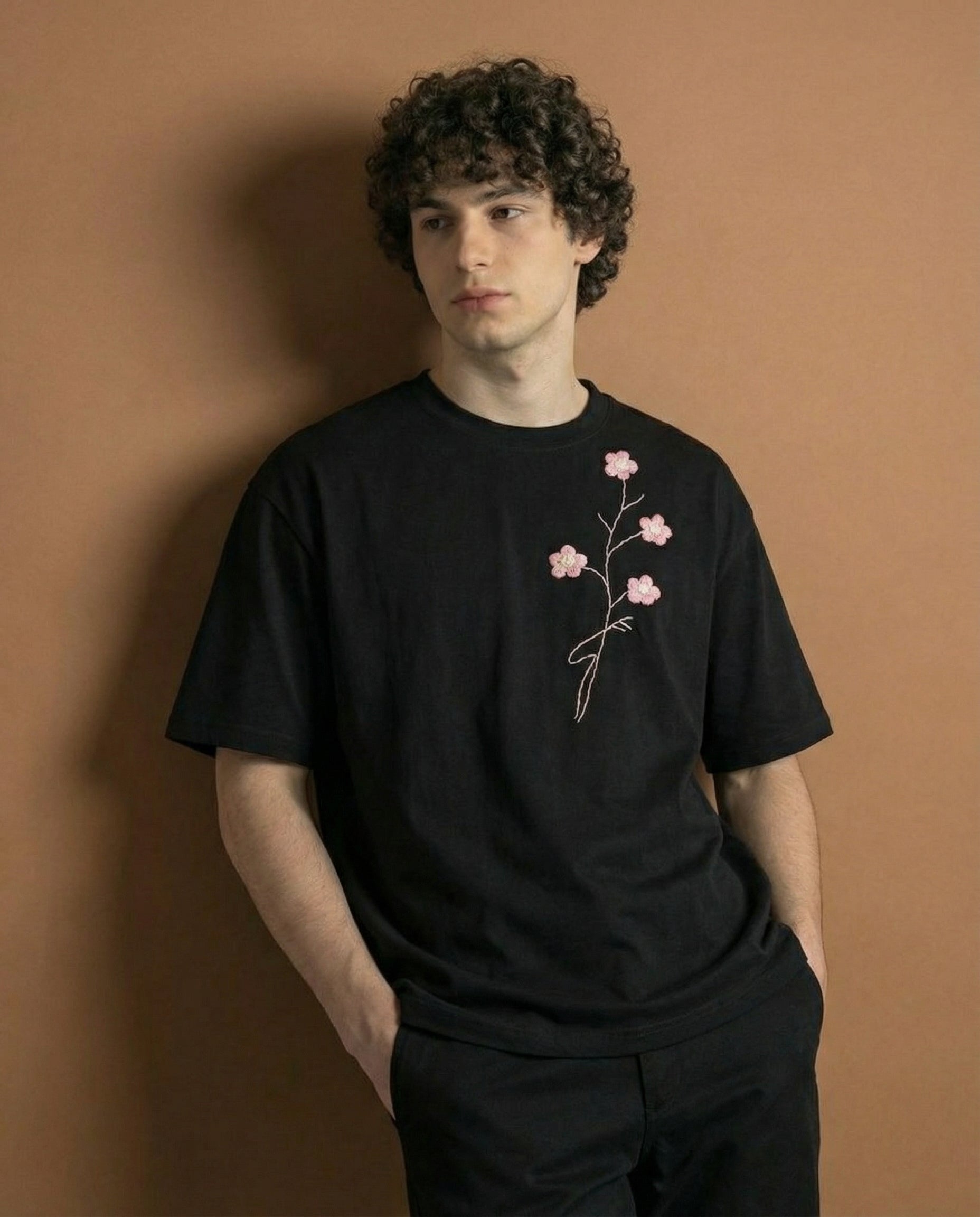 Person wearing a black t-shirt with a floral design against a brown background