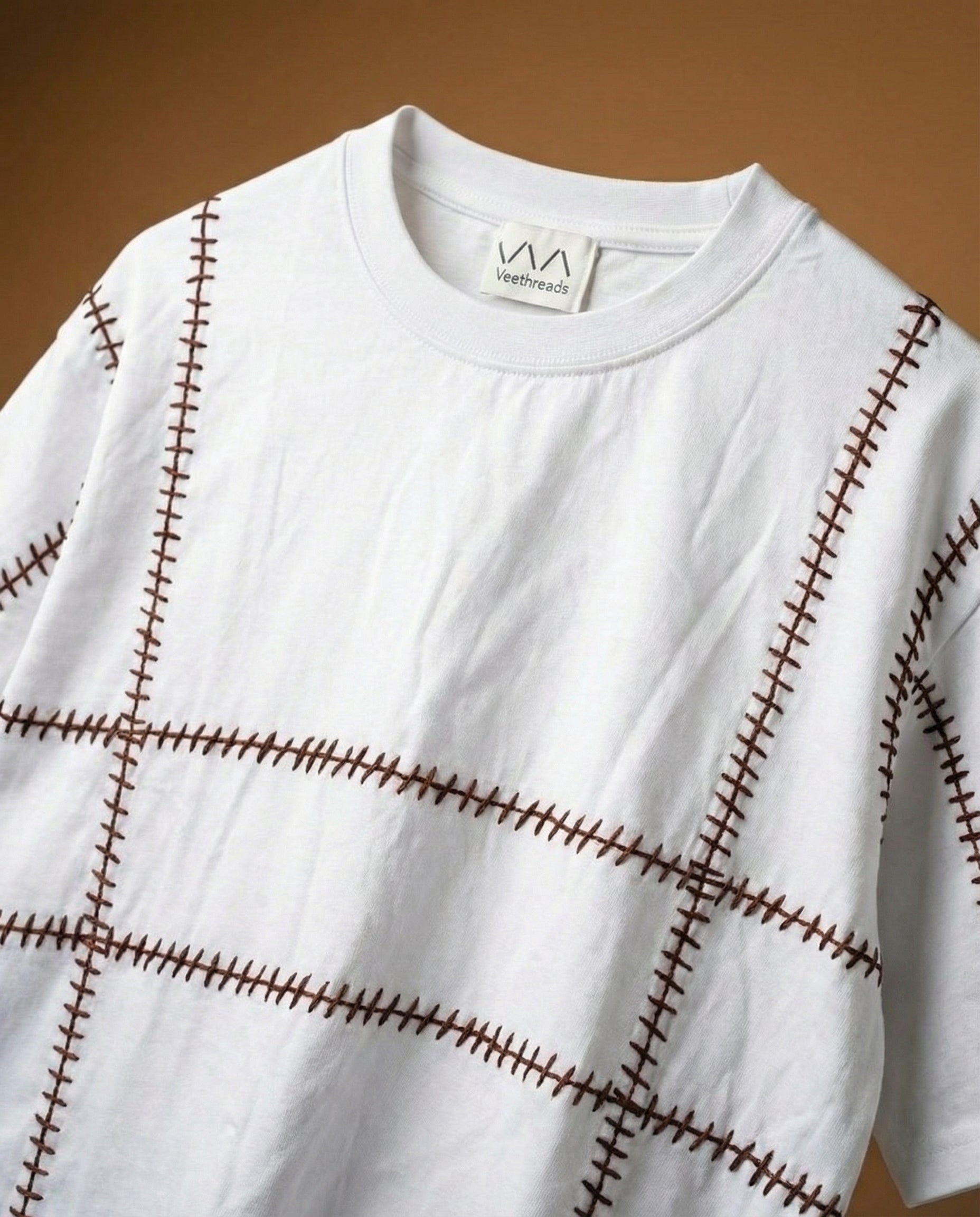 Gridlock embroidered oversized t-shirt — white cotton tee with brown geometric hand-embroidered stitching pattern, oversized fit