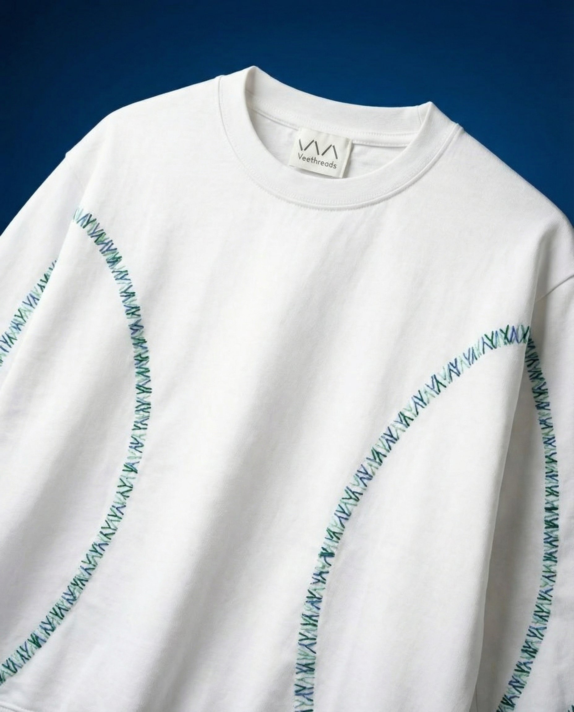 White sweatshirt with blue embroidered stitching on a blue background
