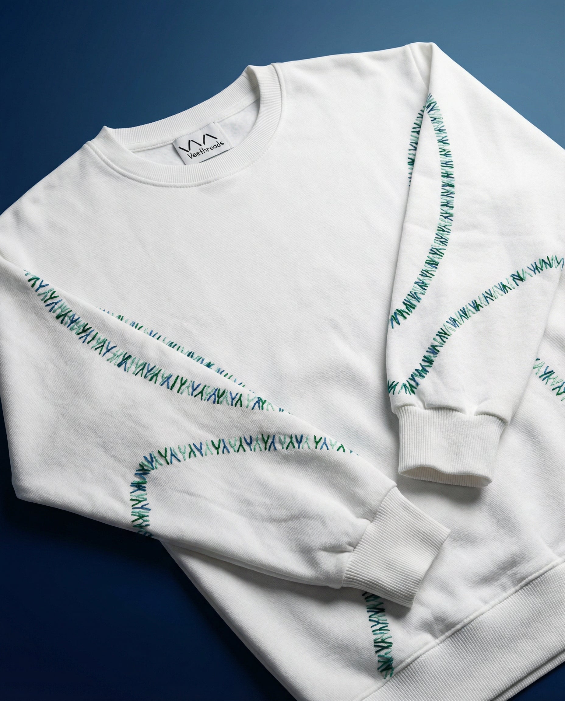 Custom sweater embroidery baseball stitch — white sweatshirt with hand-stitched baseball seam pattern in real thread