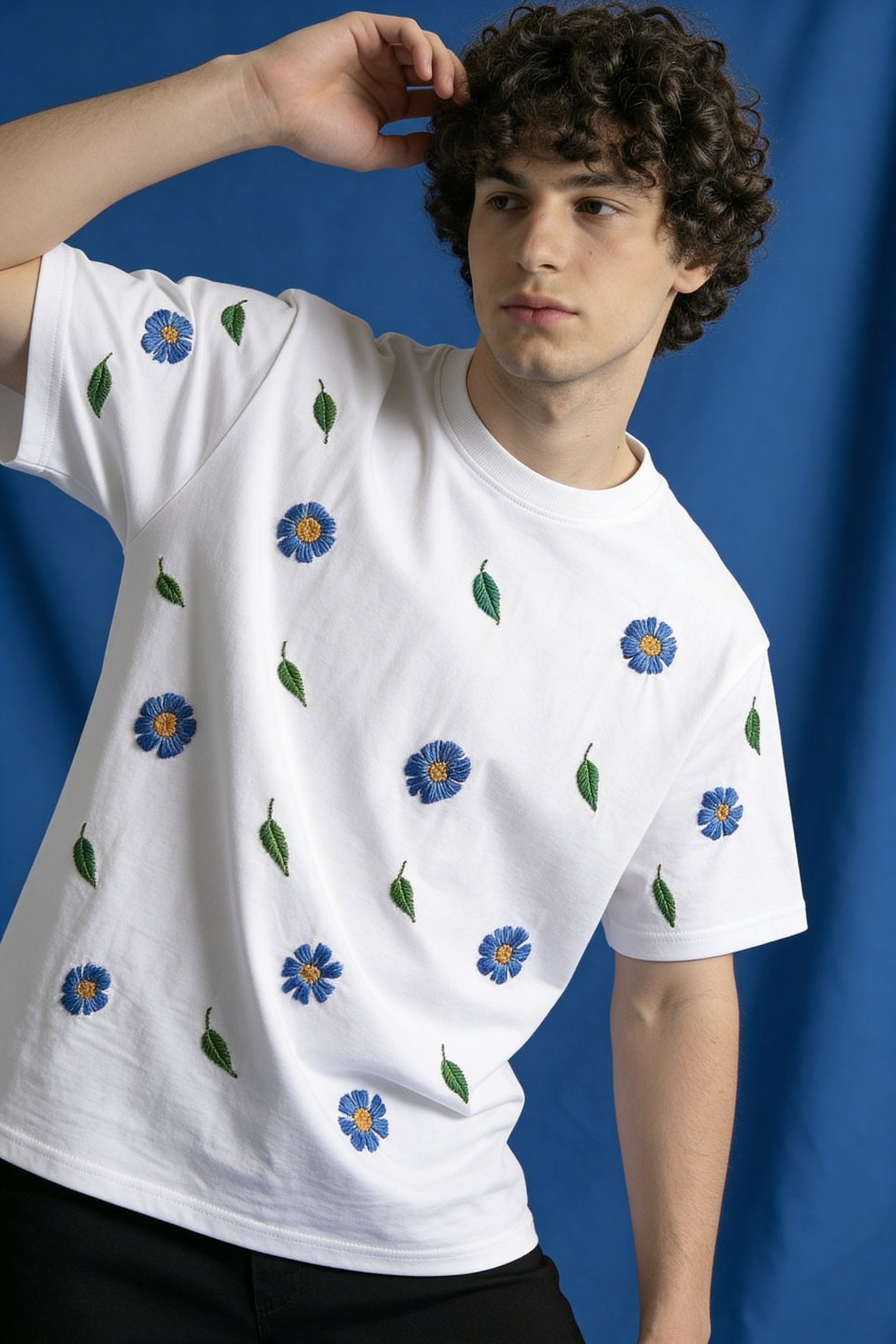 Person wearing a white t-shirt with blue floral patterns against a blue background