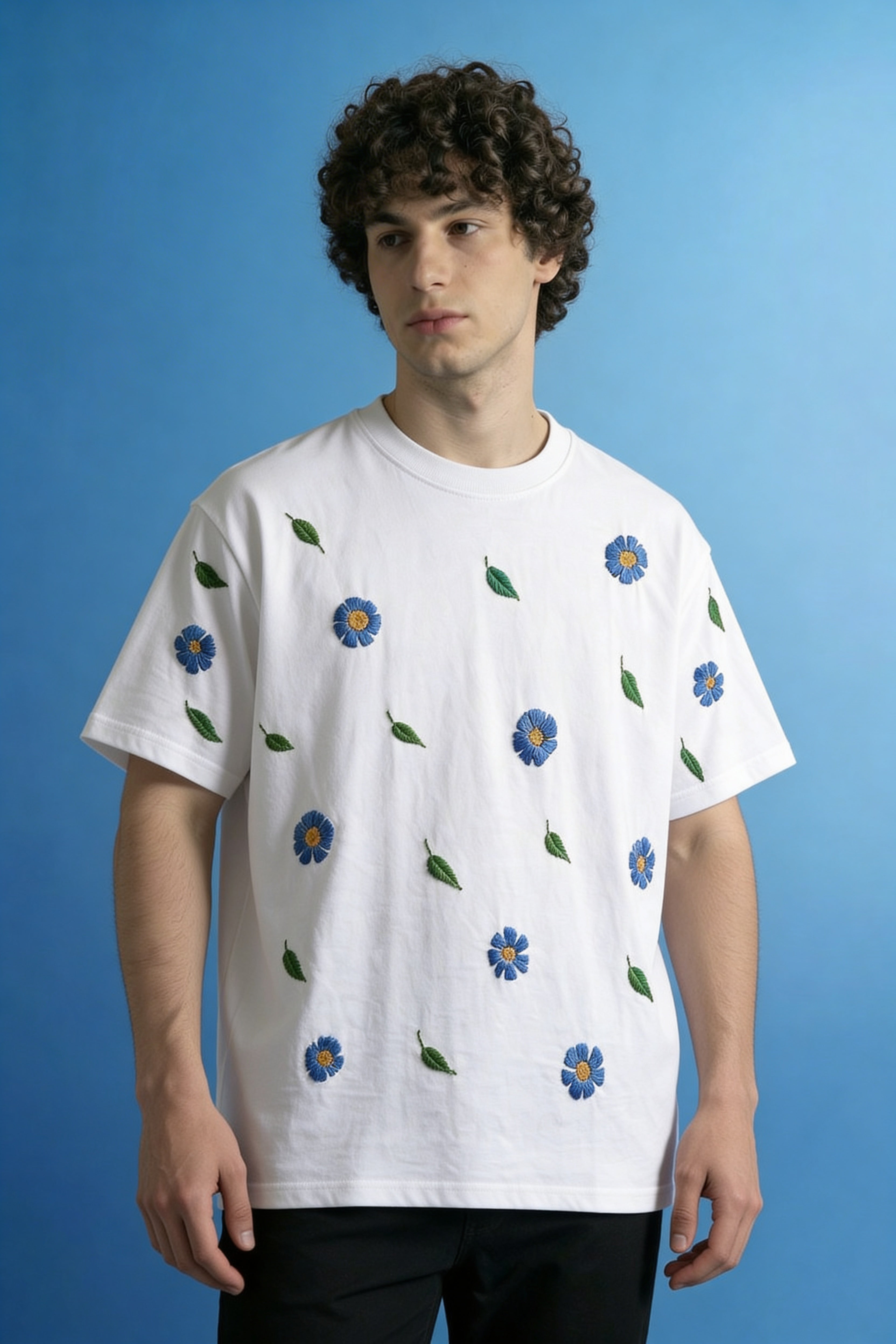 Person wearing a white t-shirt with blue floral patterns against a blue background