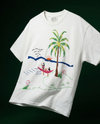 White t-shirt with a colorful embroidery design of a palm tree and beach scene on a black background