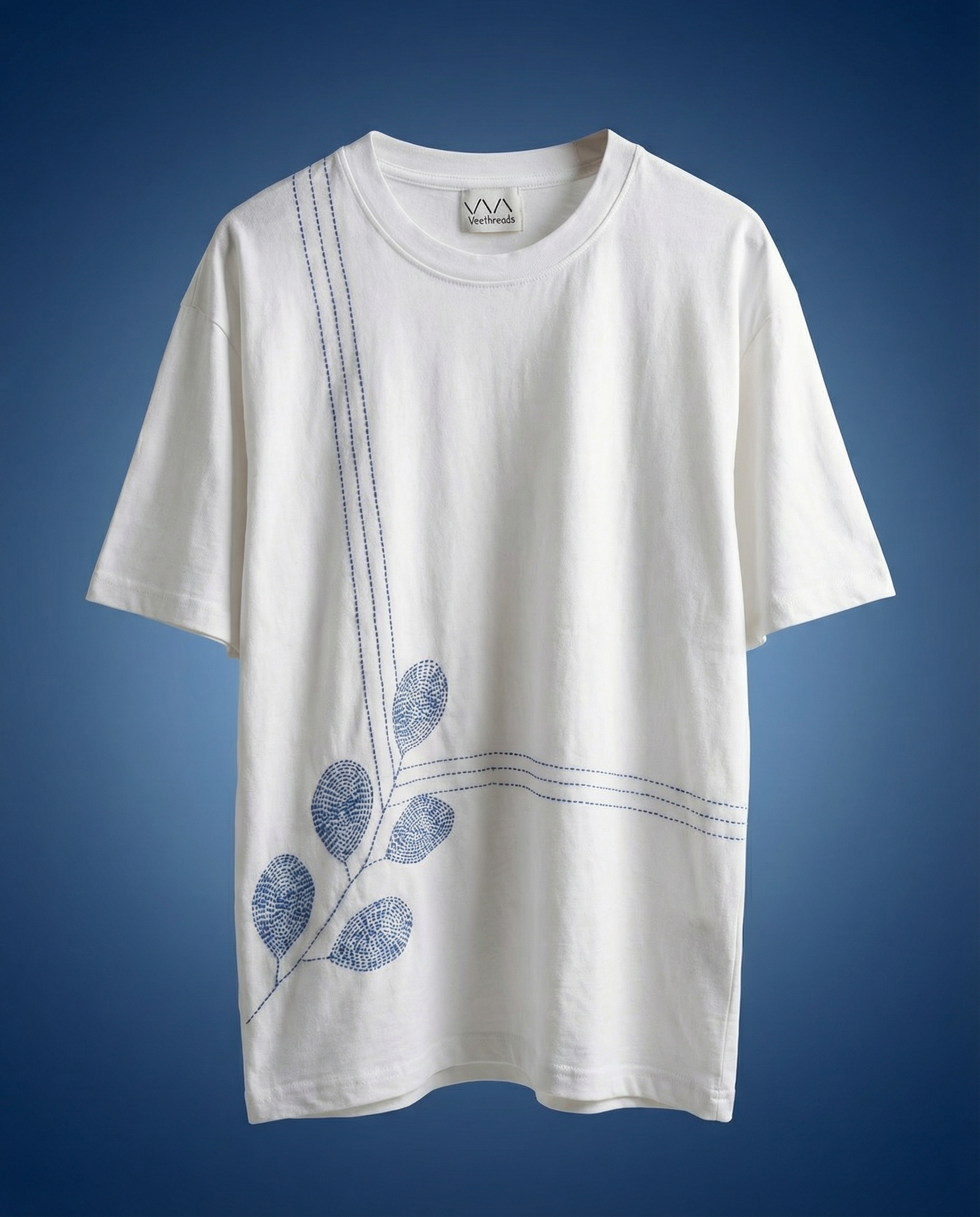 White t-shirt with blue leaf design embroidered on a blue background