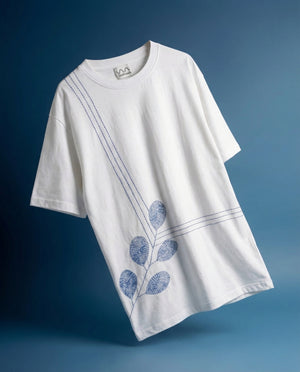 White t-shirt with blue leaf embroidery on a blue background