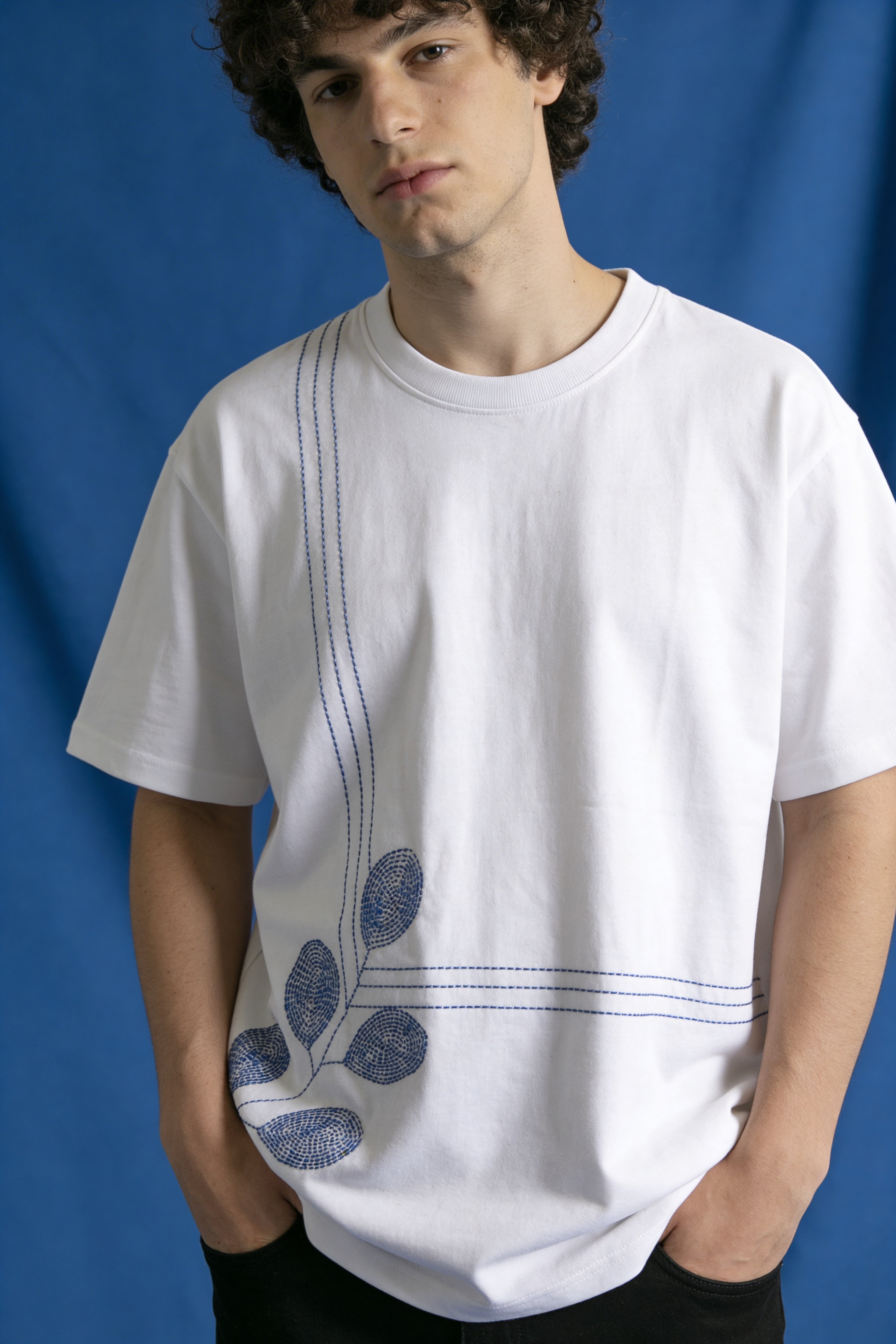 Person wearing a white t-shirt with blue leaf design against a blue background