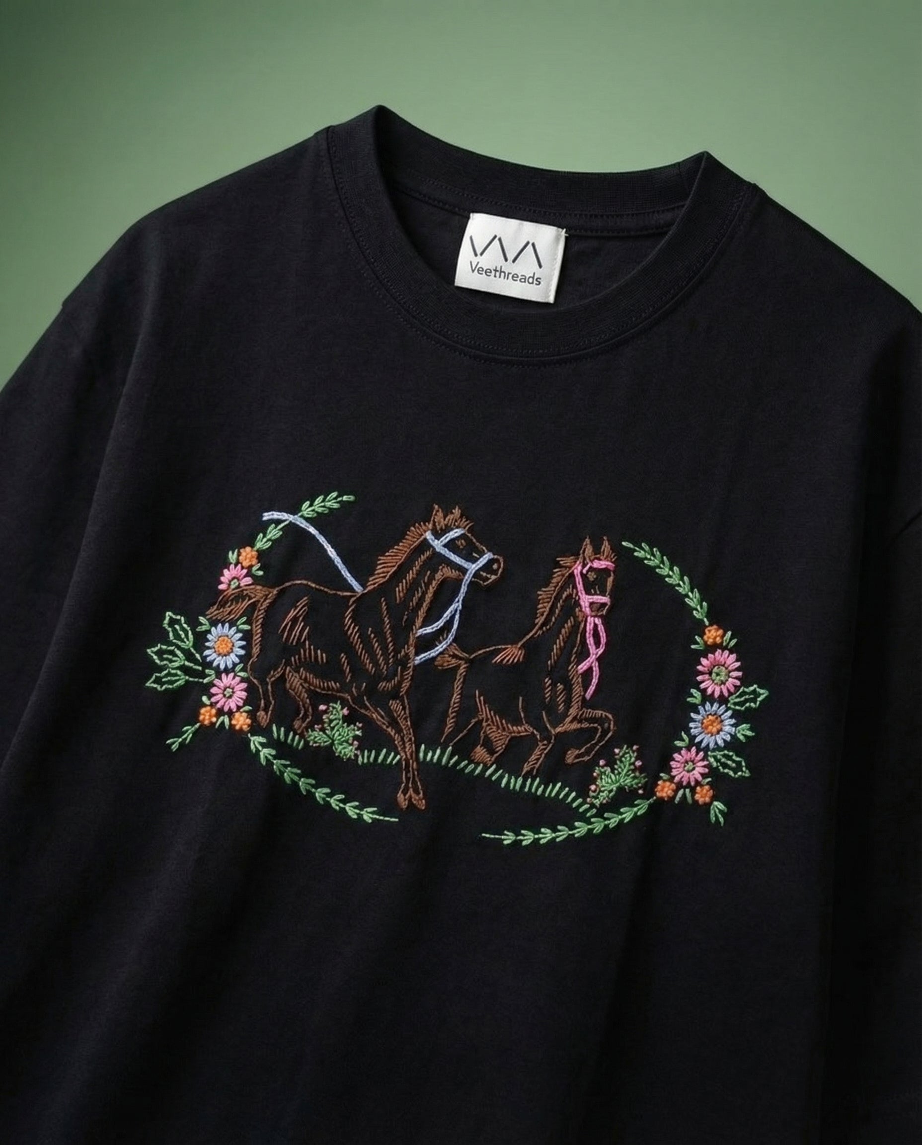 Black sweatshirt with embroidered horses and flowers on a green background